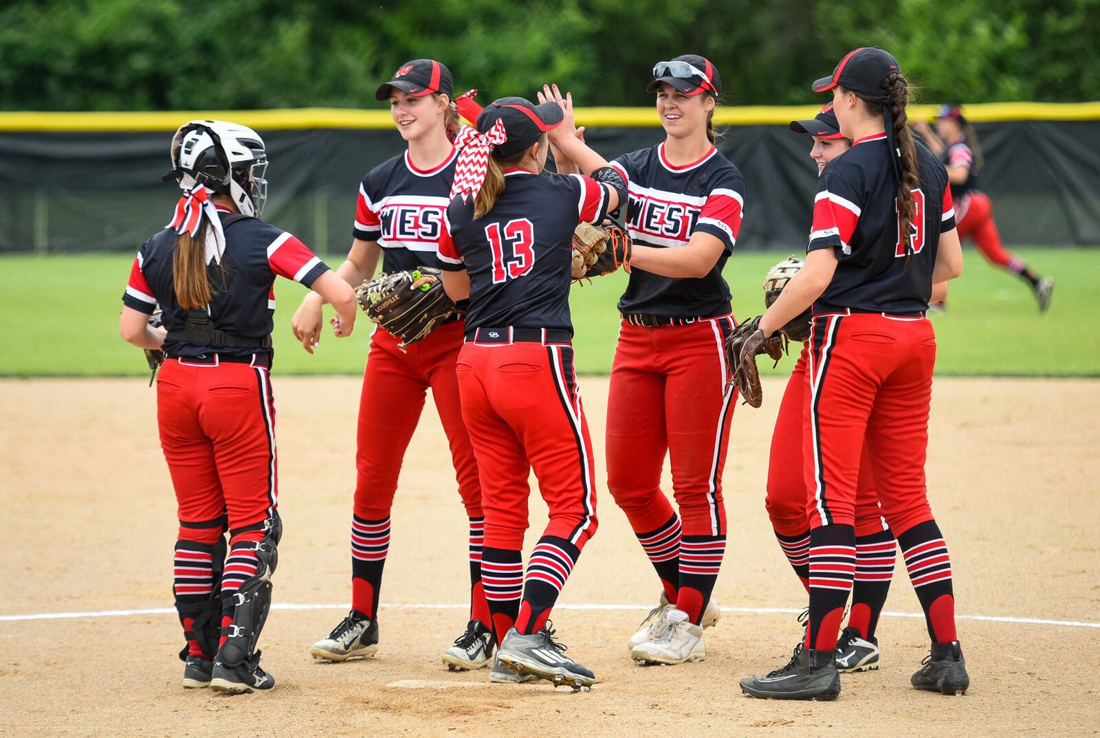 Lakota West pitcher Megan Brankamp (13) meets with teammates in the pitching circle Wednesday during a Division I regional semifinal against Lebanon at Centerville. NICK GRAHAM/STAFF