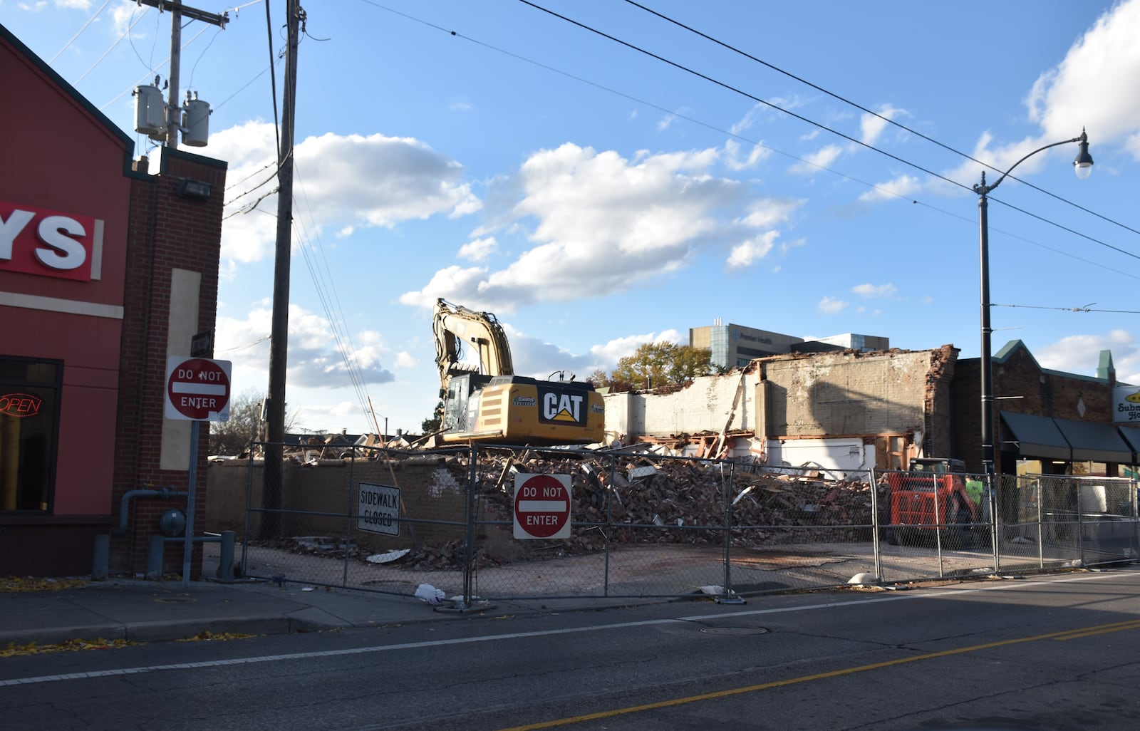 Crews tear down a former University of Dayton storage building at 1141 Brown St., located between Five Guys and the Submarine House. The property owner hopes to bring a new Dutch Bros Coffee shop to the site. CORNELIUS FROLIK / STAFF