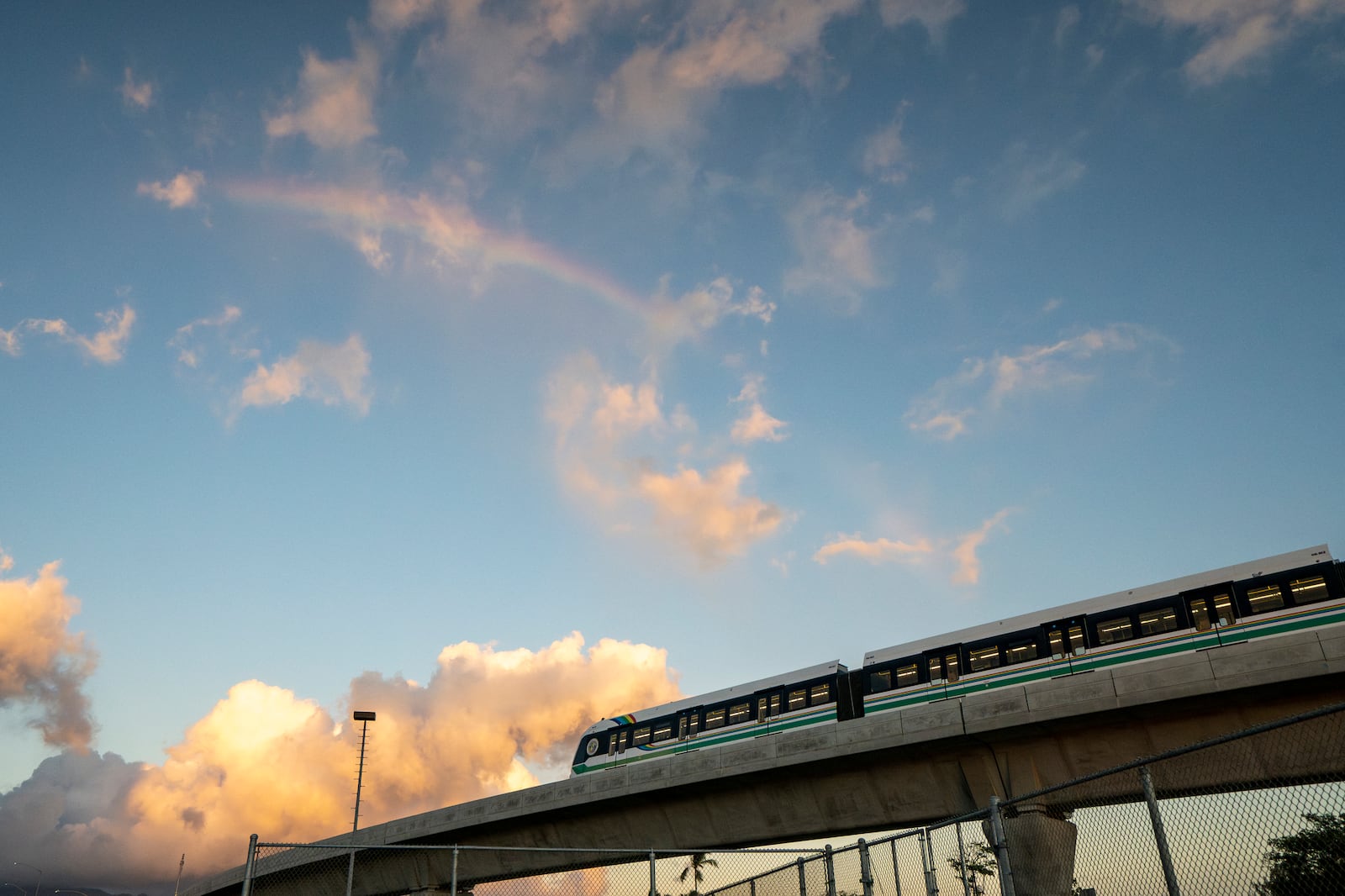 A rainbow arches over a Honolulu Skyline train at sunset, Thursday, Sept. 19, 2024, in Honolulu. (AP Photo/Mengshin Lin)