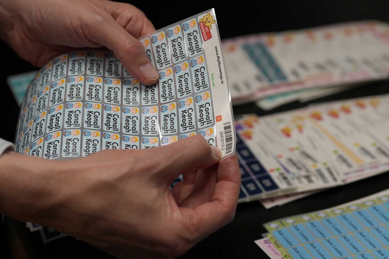 Lars Andersen founder of 'My Nametags' holds up school children labels with the necessary bar codes at his factory in London, Thursday, Jan. 30, 2025. (AP Photo/Alastair Grant)