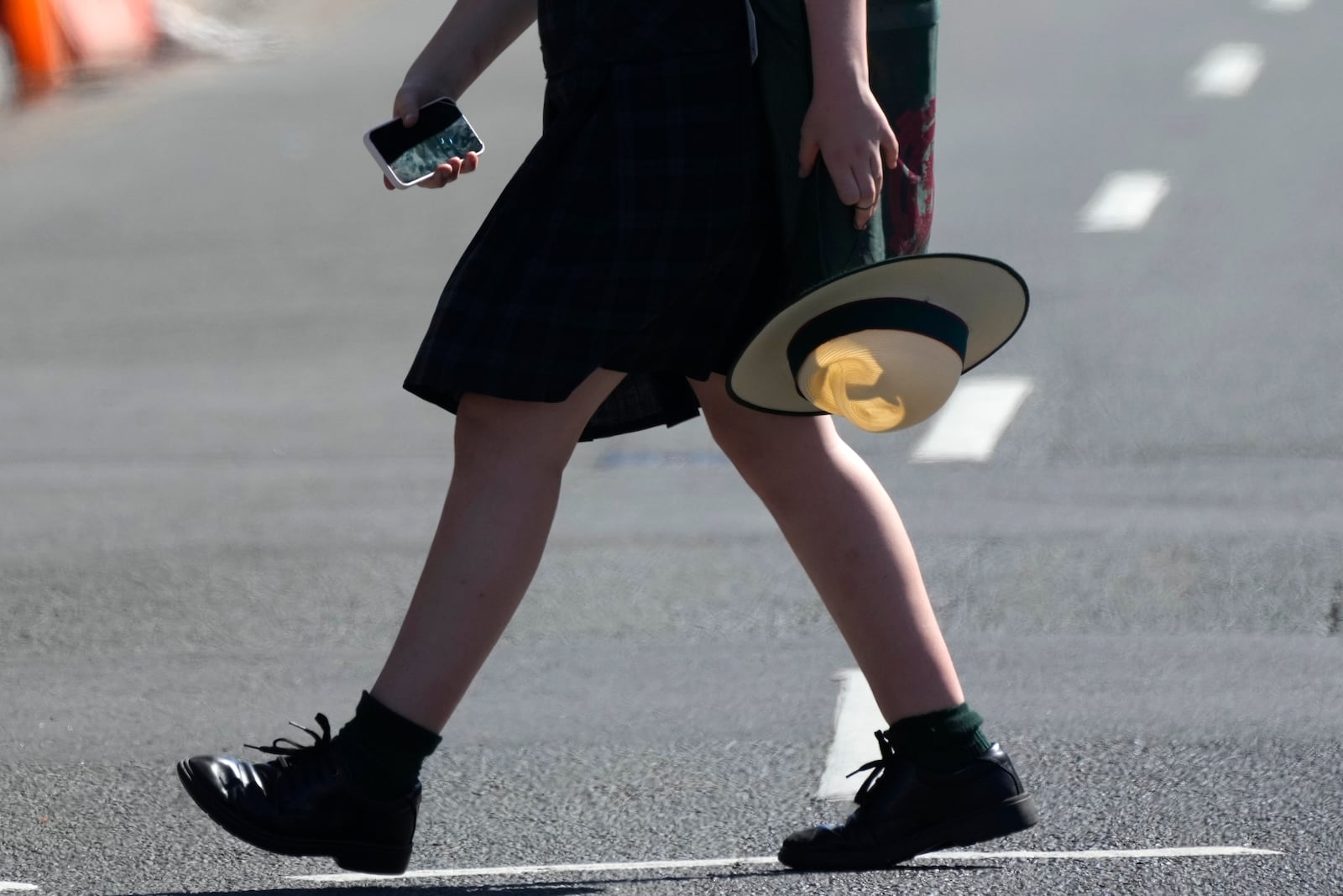 A school girl holds her phone while crossing a street in Sydney, Friday, Nov. 8, 2024. (AP Photo/Rick Rycroft)