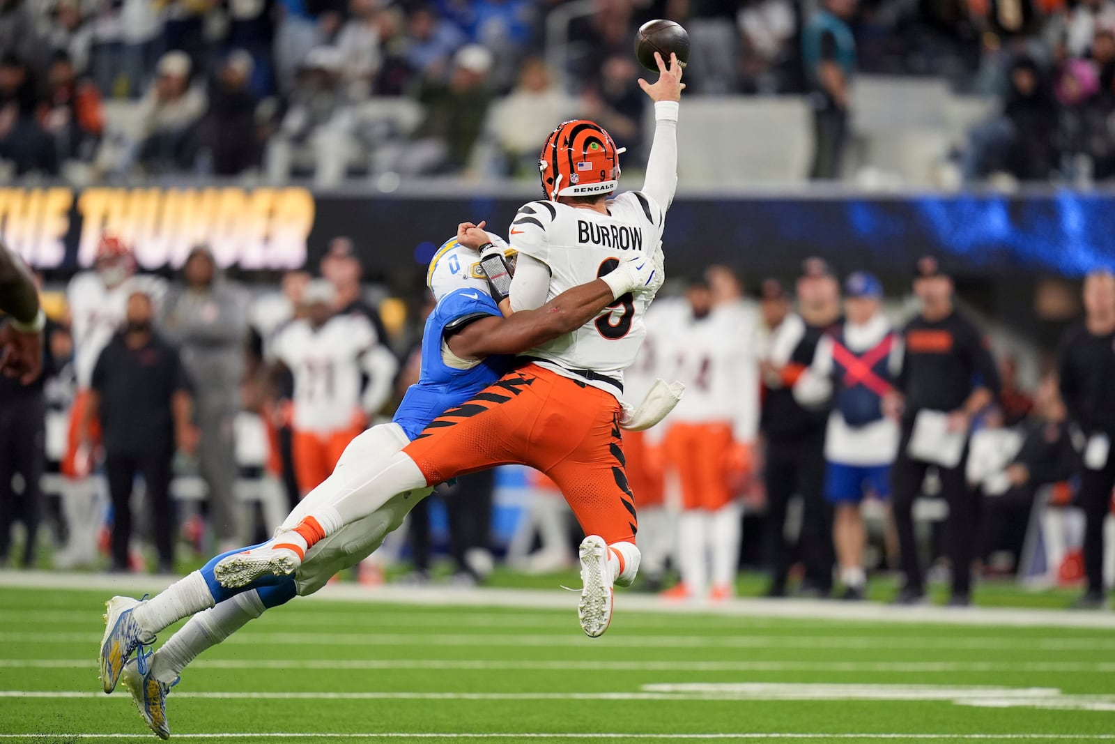 Cincinnati Bengals quarterback Joe Burrow (9) throws as he is tackled by Los Angeles Chargers linebacker Daiyan Henley (0) during the second half of an NFL football game Sunday, Nov. 17, 2024, in Inglewood, Calif. (AP Photo/Gregory Bull)