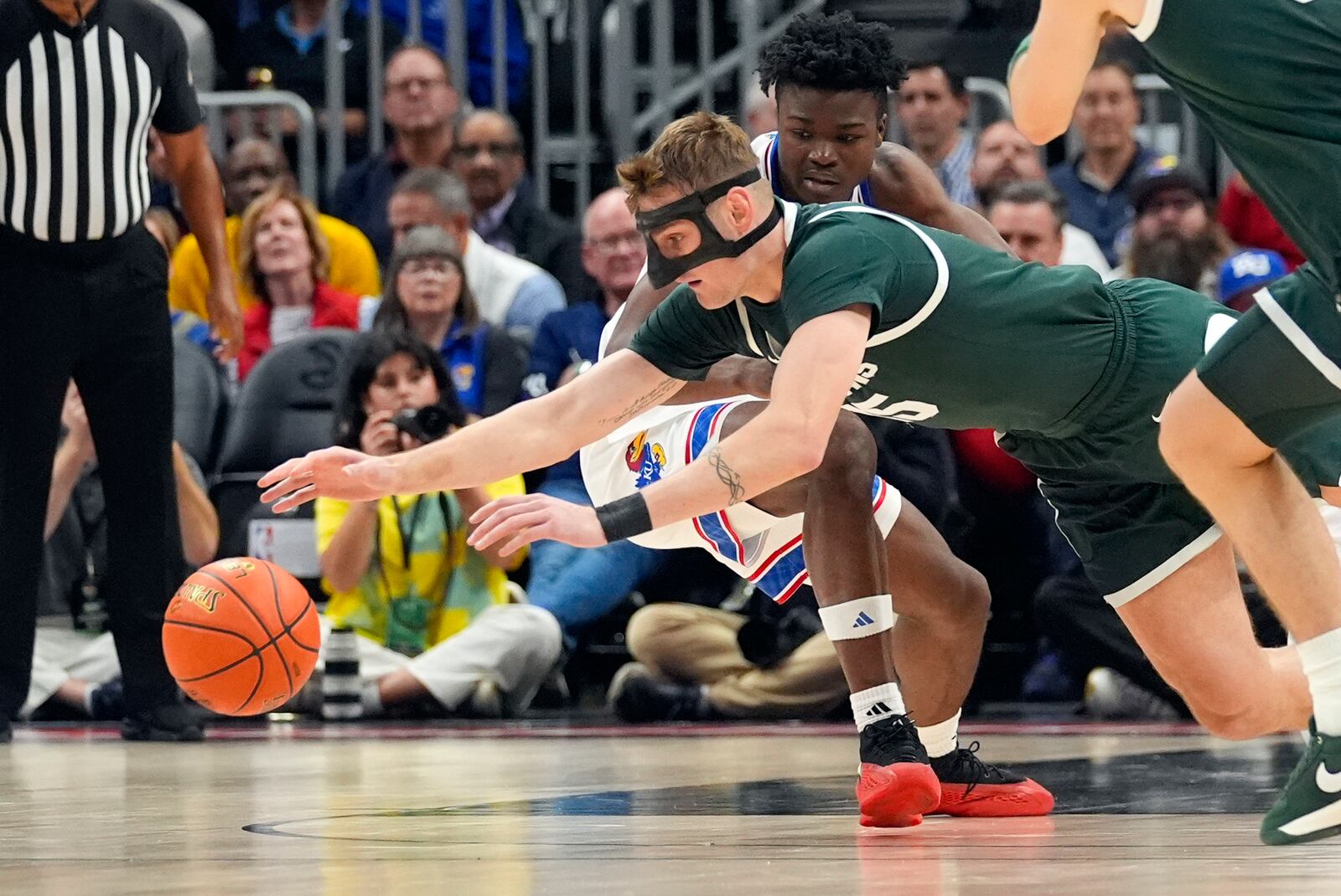 Michigan State center Carson Cooper (15) and Kansas guard Rakease Passmore (4) chase down a loose ball during the first half of an NCAA college basketball game, Tuesday, Nov. 12, 2024, in Atlanta. (AP Photo/John Bazemore )