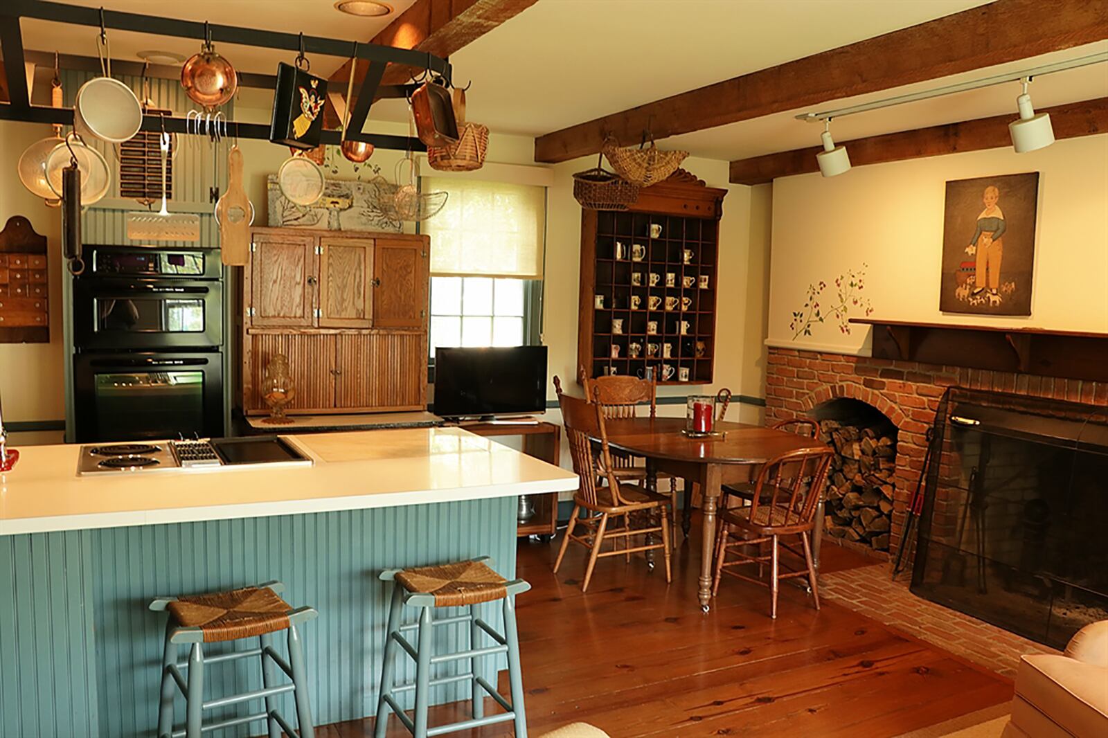 A galley kitchen features a commercial gas range and exhaust fan. Next to the range is a preparation counter with ceramic-tile countertop and barn-beam shelves that surround a window. A double sink is below a side window and has a butcher-block countertop above the dishwasher. CONTRIBUTED PHOTO BY KATHY TYLER