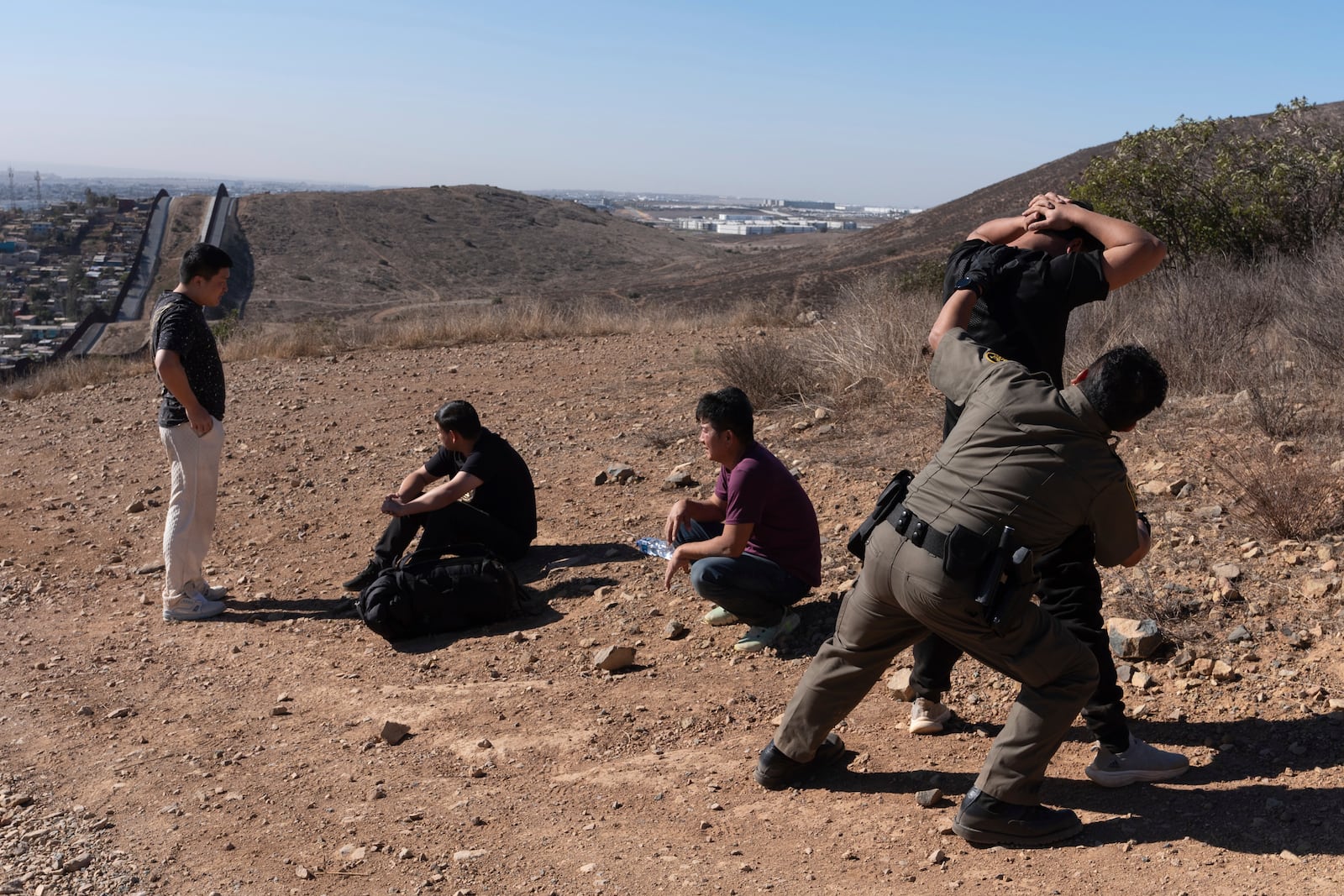 Border Patrol Agent Gutierrez, right, pats down one of four men after the group crossed the border illegally through a gap in two walls separating Mexico from the United States before turning themselves in, Thursday, Jan. 23, 2025, in San Diego. (AP Photo/Gregory Bull)