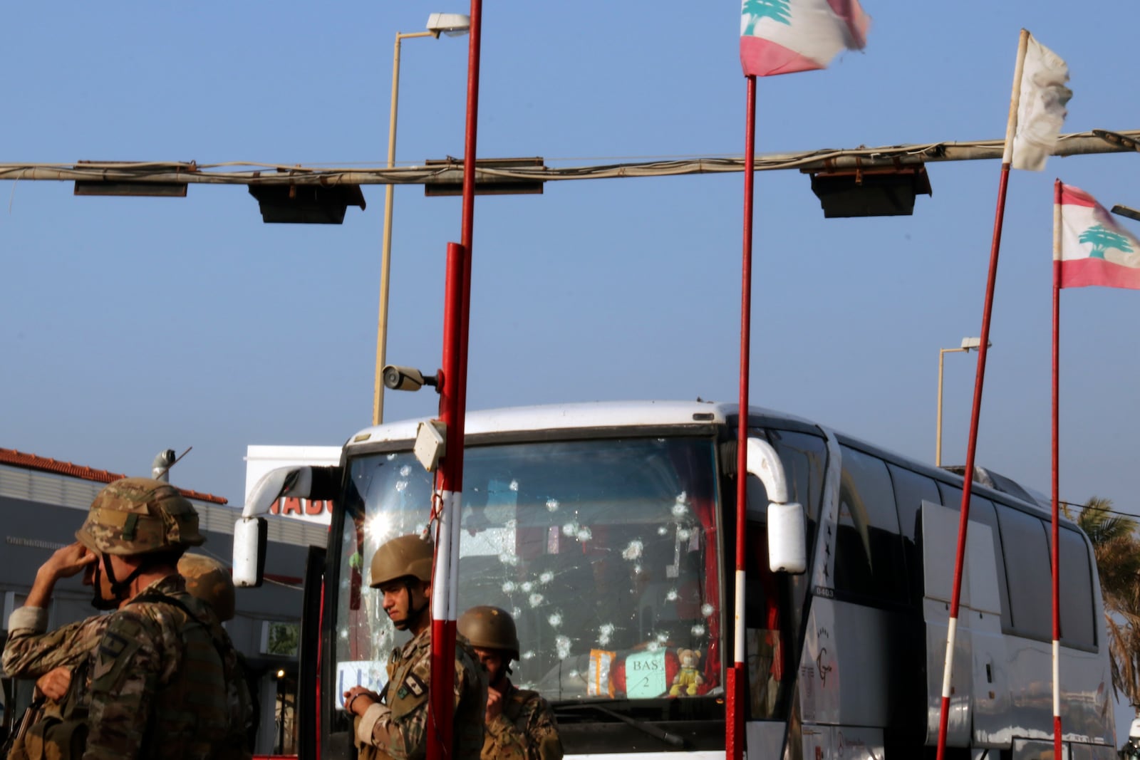 In this handout photo, Lebanese army soldiers stand guard next to a damaged bus of the Malaysian U.N. peacekeepers at the site of an Israeli strike hit a car, in the southern port city of Sidon, Lebanon, Thursday, Nov. 7, 2024. (AP Photo)