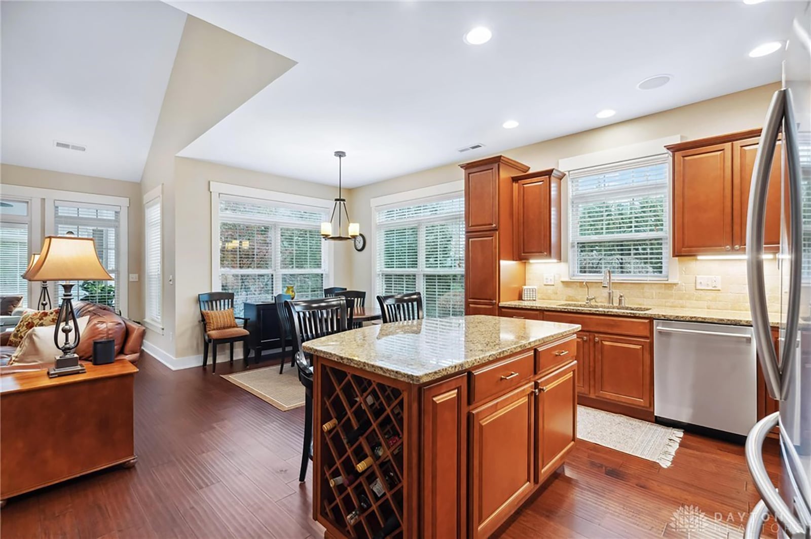 The kitchen and dining area have hardwood flooring and stainless appliances as well as an island with additional seating.