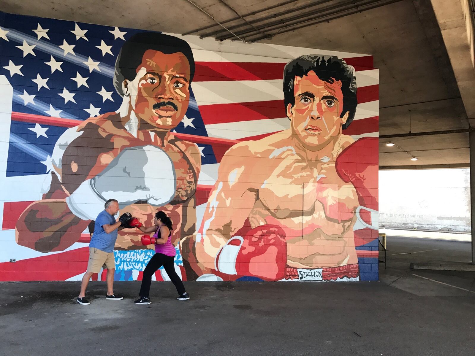 Dr. Luxme Hariharan – who does boxing workouts 2 to 3 days a week at Drake’s Downtown Gym before heading to Dayton Children’s Hospital where she is the new Chief of Ophthalmology and Chief Population Health Officer – hits the mitts held by John Drake, the fight club’s owner and trainer John Drake, duting a session  in front of the Apollo Creed/ Rocky Balboa mural on the outside of the gym. Tom Archdeacon/CONTRIBUTED