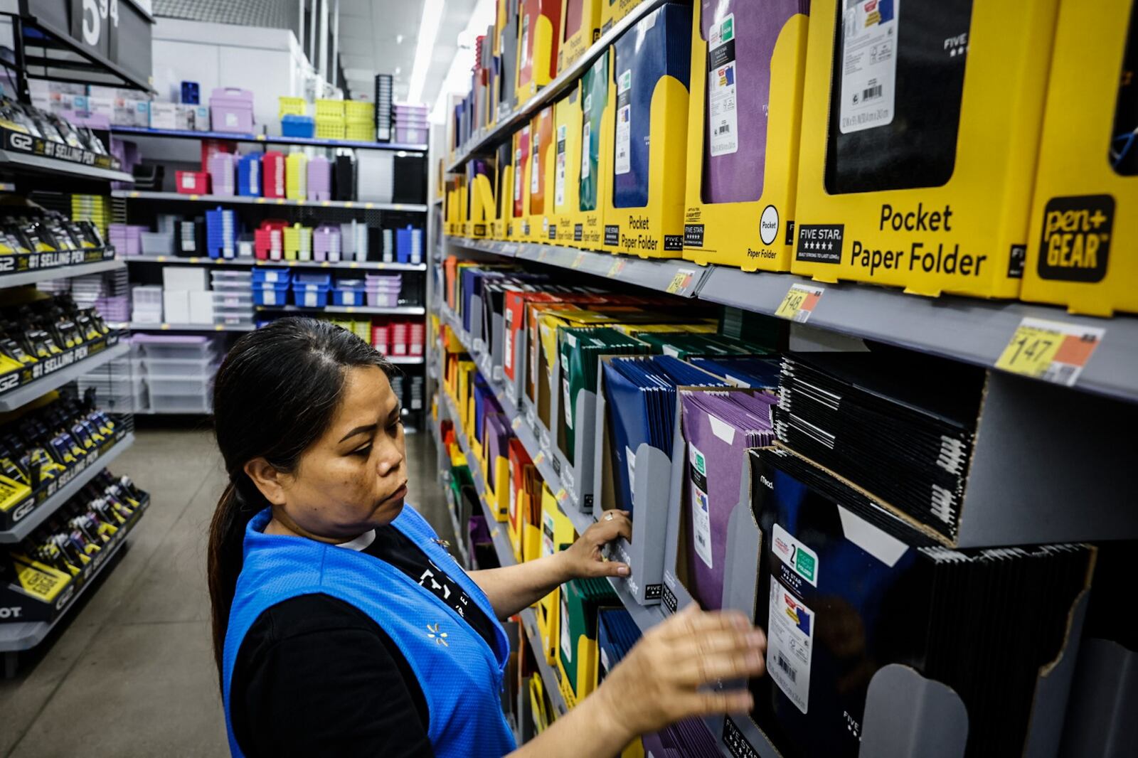 Walmart seasonal associate Rossana Becchetti straightens school supplies in the racks at the Walmart in Beavercreek Thursday July 25, 2024. JIM NOELKER/STAFF