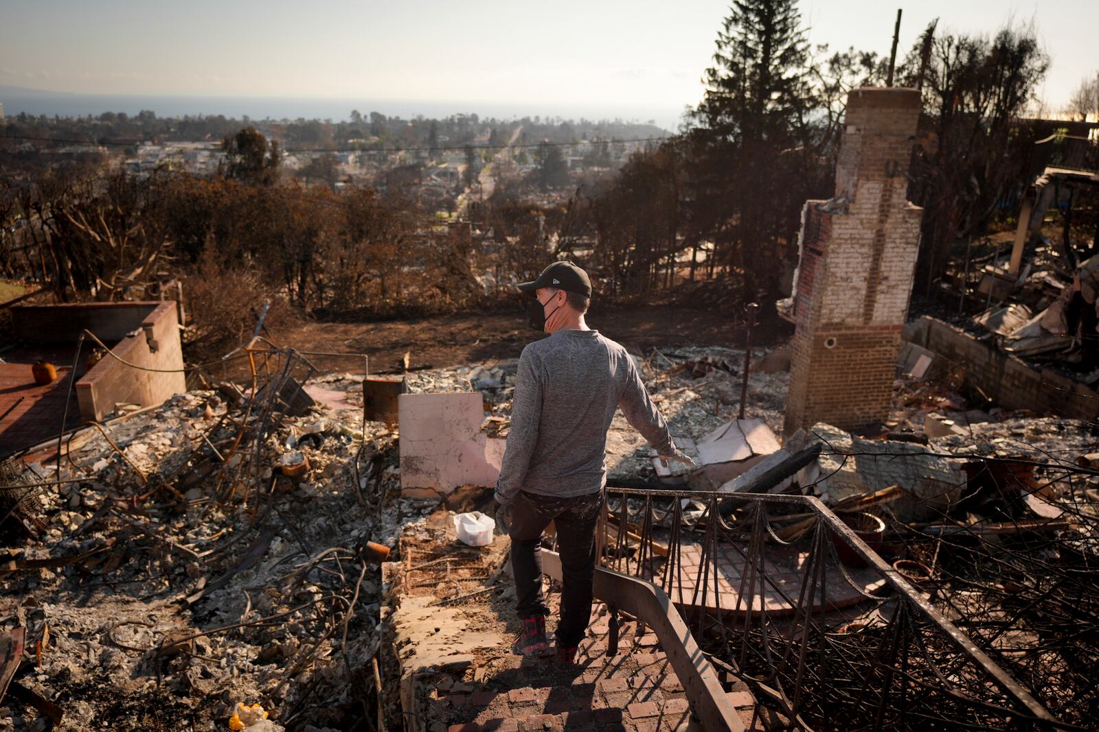 Tim Bearer walks in the rubble of his mother's fire-ravaged property in the aftermath of the Palisades Fire in the Pacific Palisades neighborhood of Los Angeles, Tuesday, Jan. 28, 2025. (AP Photo/Jae C. Hong)