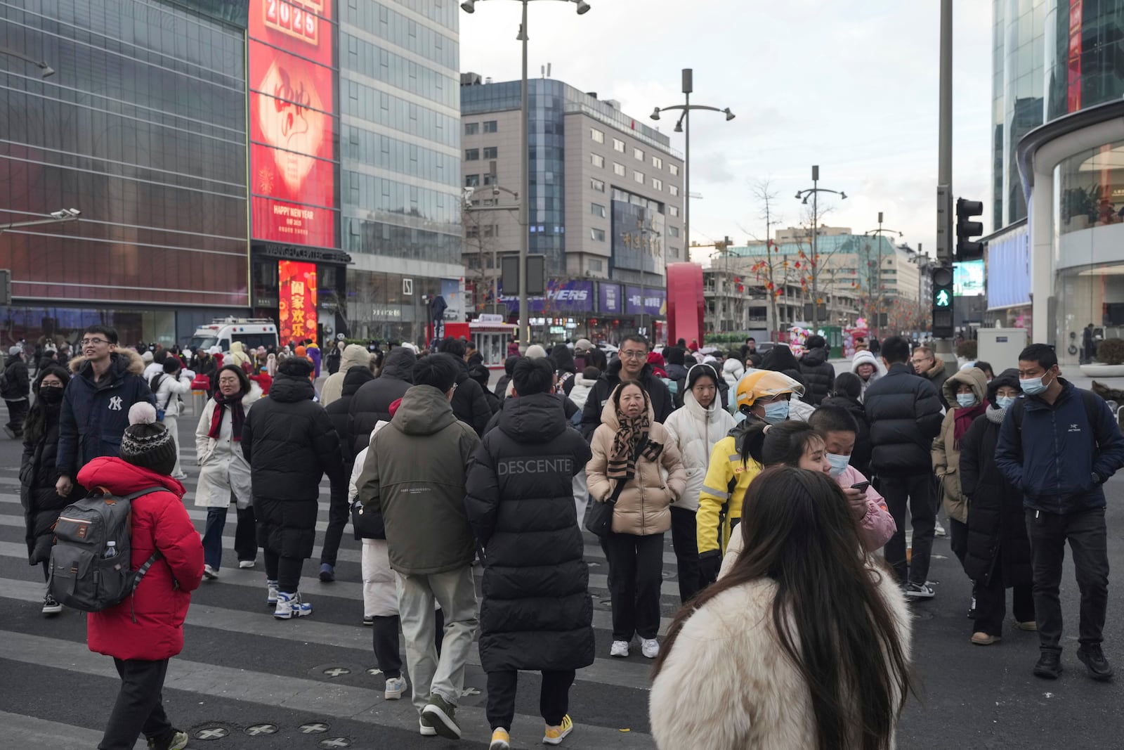 People cross a road at a shopping area in Beijing on Tuesday, Feb. 4, 2025. (AP Photo/Aaron Favila)