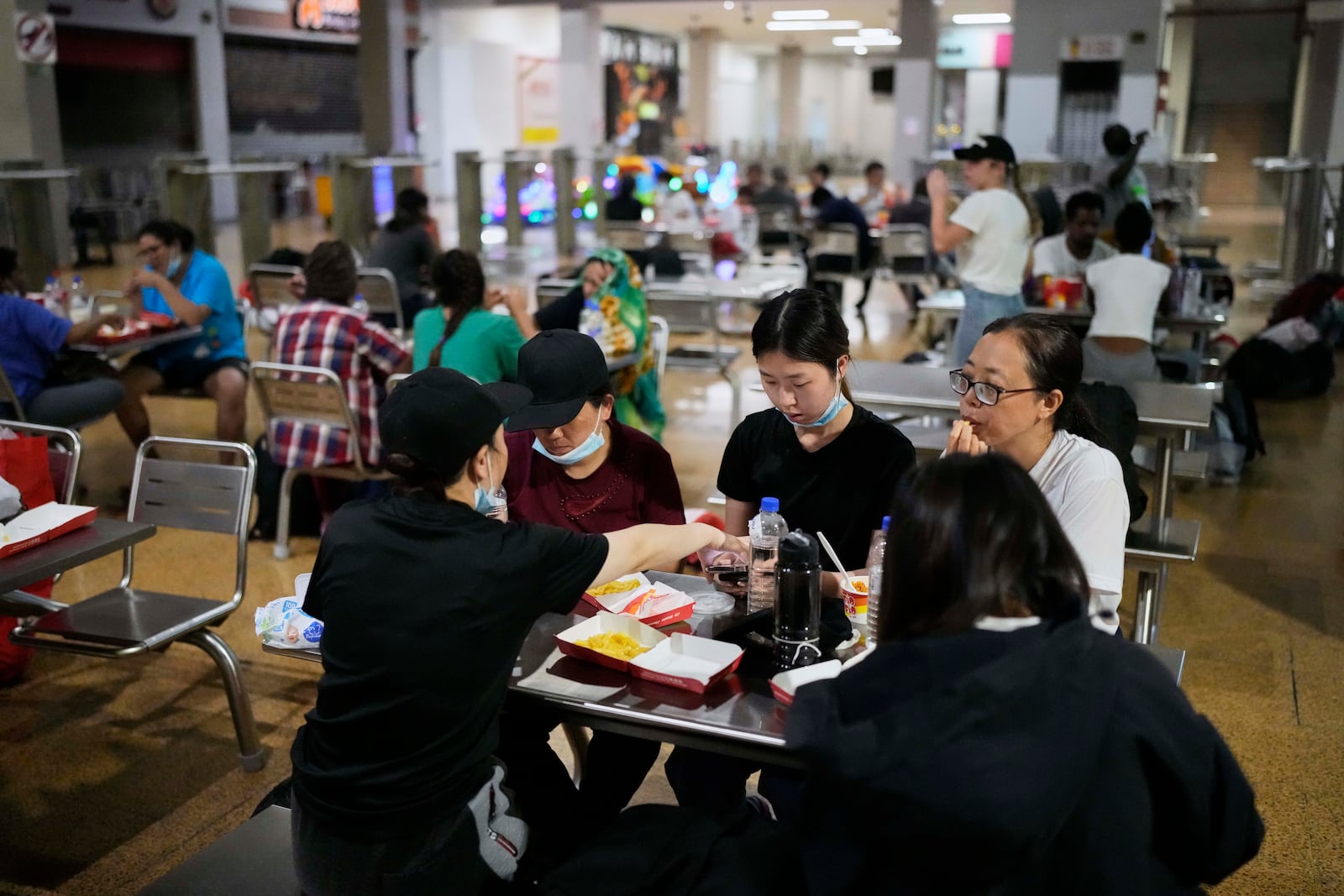 Chinese migrants eat at a bus station food court after arriving in Panama City, Saturday, March 8, 2025, after spending weeks in a Panamanian immigration camp where they were held following their deportation from the U.S. and released on the condition that they leave the country within 30 days. (AP Photo/Matias Delacroix)