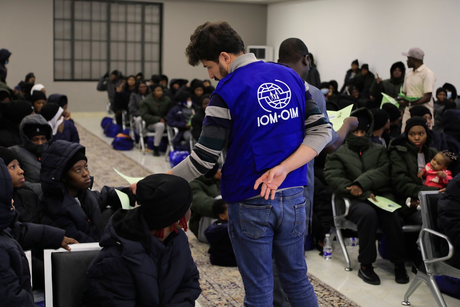 An official from the International Organization for Migration, IOM, talks to Nigerian migrants before being deported from Tripoli, Libya, Tuesday, March 18, 2025. (AP Photo/Yousef Murad)