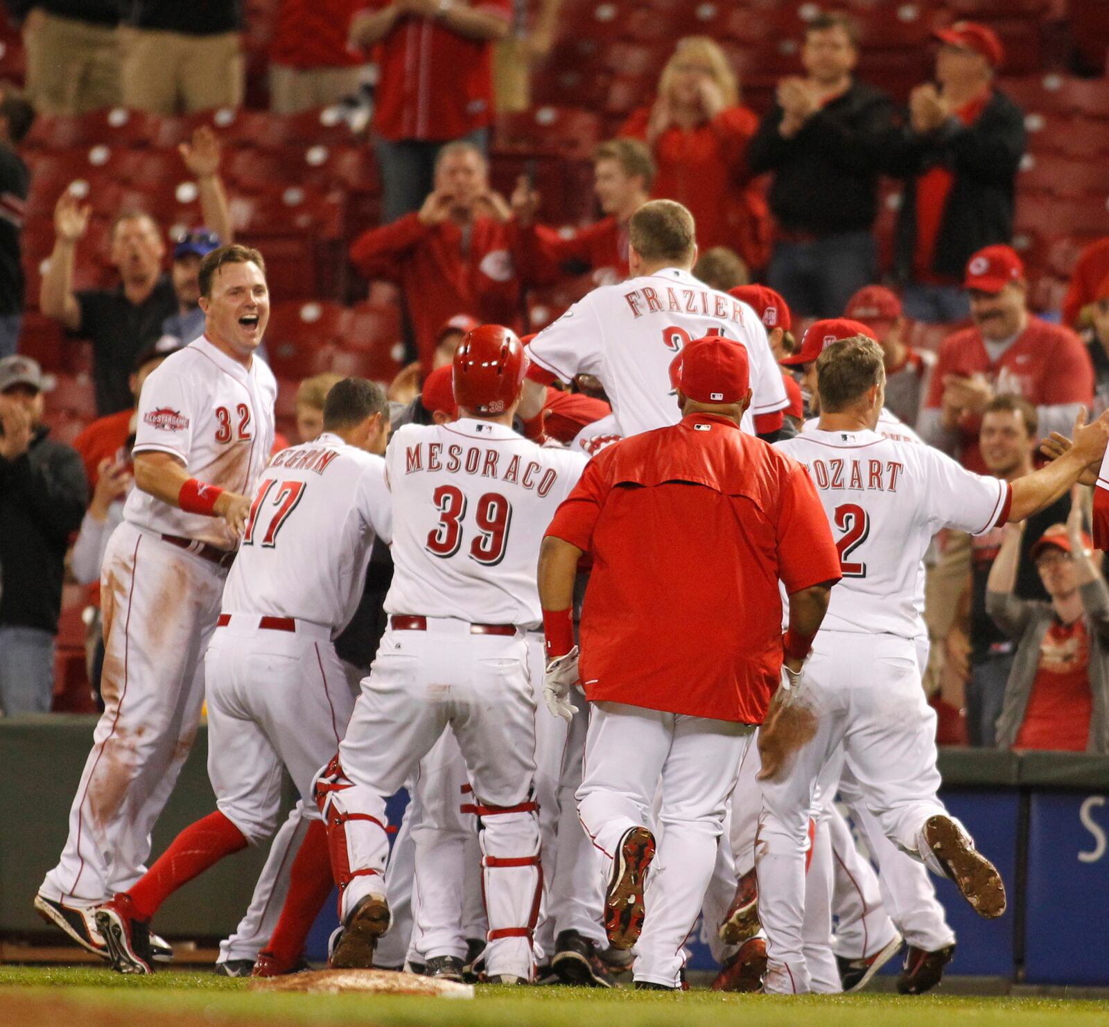 The Reds converge on Joey Votto after his game-winning hit in the 11th inning against the Pirates on Wednesday, April 8, 2015, at Great American Ball Park in Cincinnati.