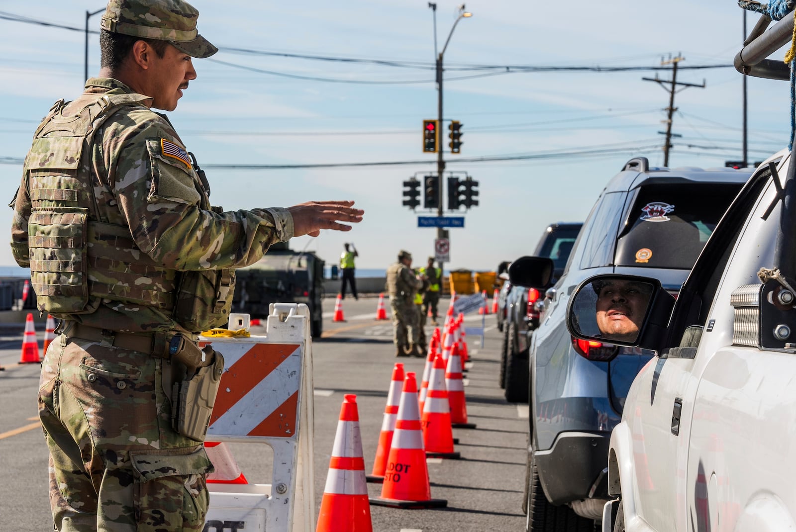 Members of the National Guard check the I.D. of construction workers and residents as they drive in at a checkpoint as President Donald Trump sets to tour the Palisades Fire zone damage in the Pacific Palisades neighborhood of Los Angeles, Friday, Jan. 24, 2025. (AP Photo/Damian Dovarganes)