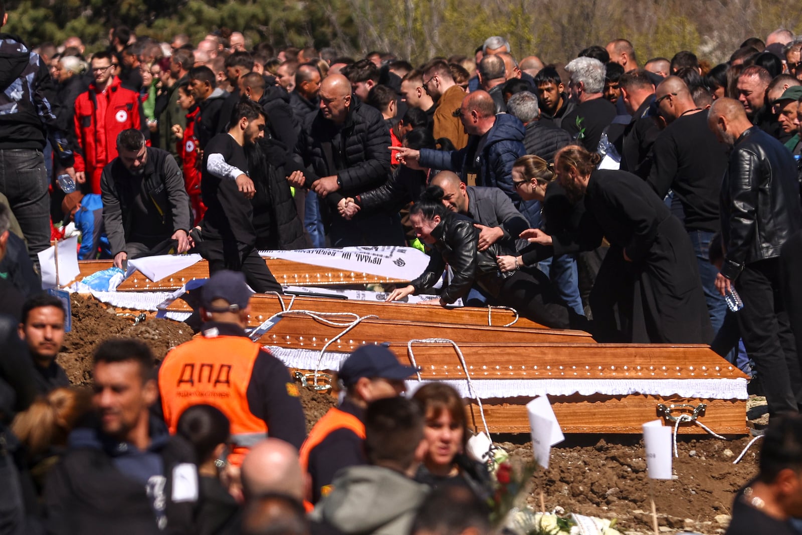 A woman leans on a coffin during the funeral ceremony of the victims of a massive nightclub fire in the town of Kocani, North Macedonia, Thursday, March 20, 2025. (AP Photo/Armin Durgut)