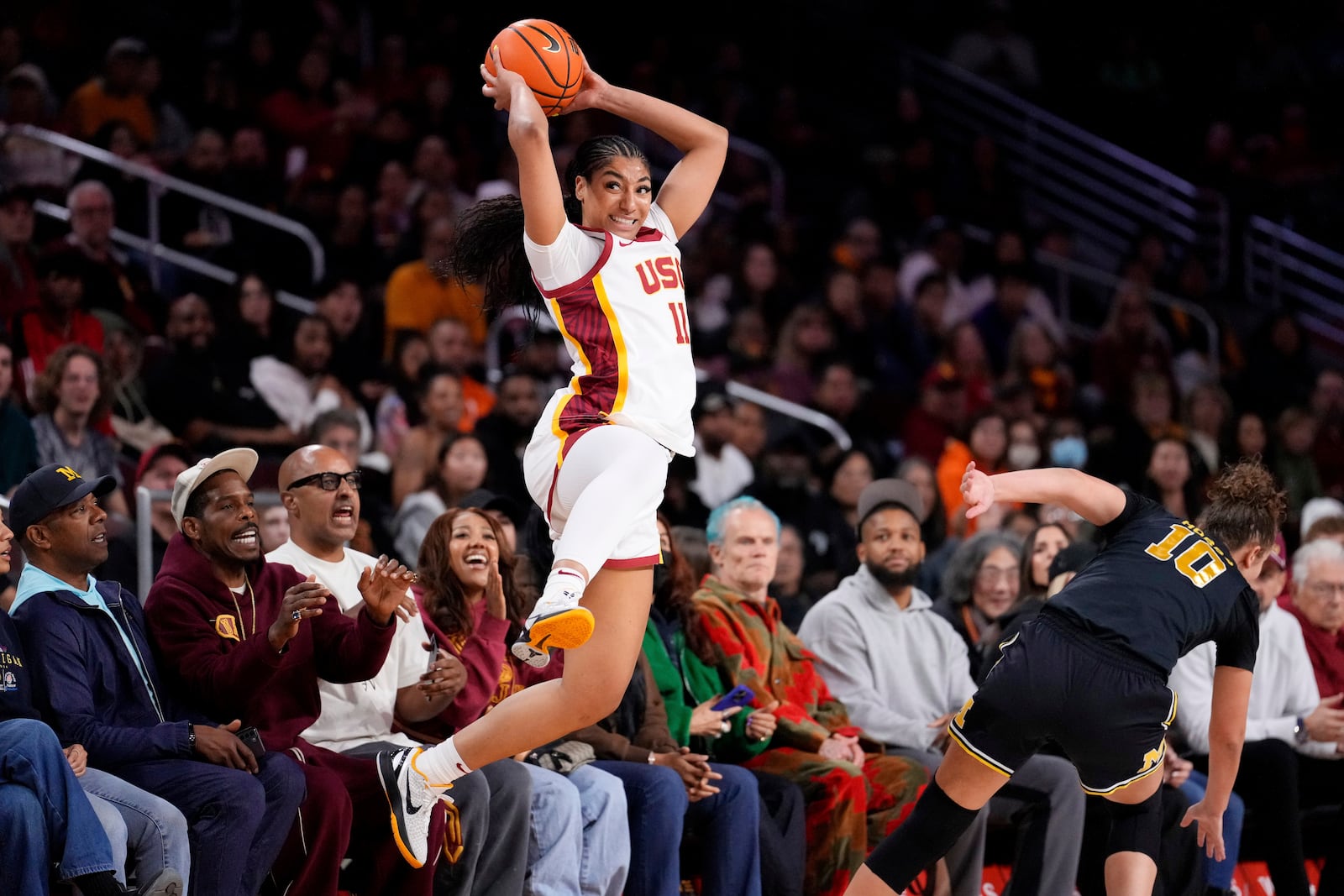 Southern California guard Kennedy Smith, left, jumps to keep the ball in bounds as Michigan guard Jordan Hobbs defends during the first half of an NCAA college basketball game, Sunday, Dec. 29, 2024, in Los Angeles. (AP Photo/Mark J. Terrill)