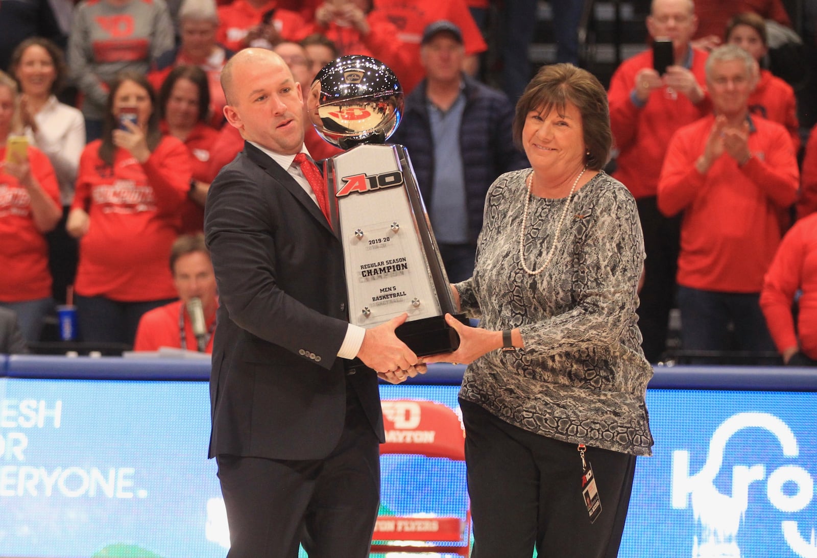 Dayton's Robbie Poteat and A-10 Commissioner Bernadette McGlade carry the A-10 championship trophy onto the tour after Dayton beat  George Washington on Senior Night on Saturday, March 7, 2020, at UD Arena.