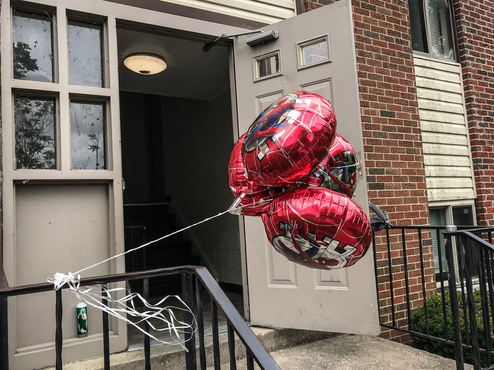 Balloons and other items make up a small memorial outside an apartment on North James H. McGee Boulevard after a young boy was found dead. STAFF PHOTO / JIM NOELKER