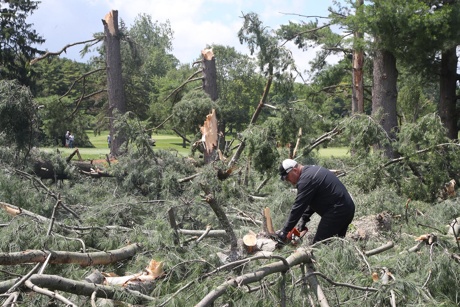 A volunteer cuts up trees Thursday, June 9, 2022, that were toppled in Wednesday's tornado at the Springfield Country Club. BILL LACKEY/STAFF