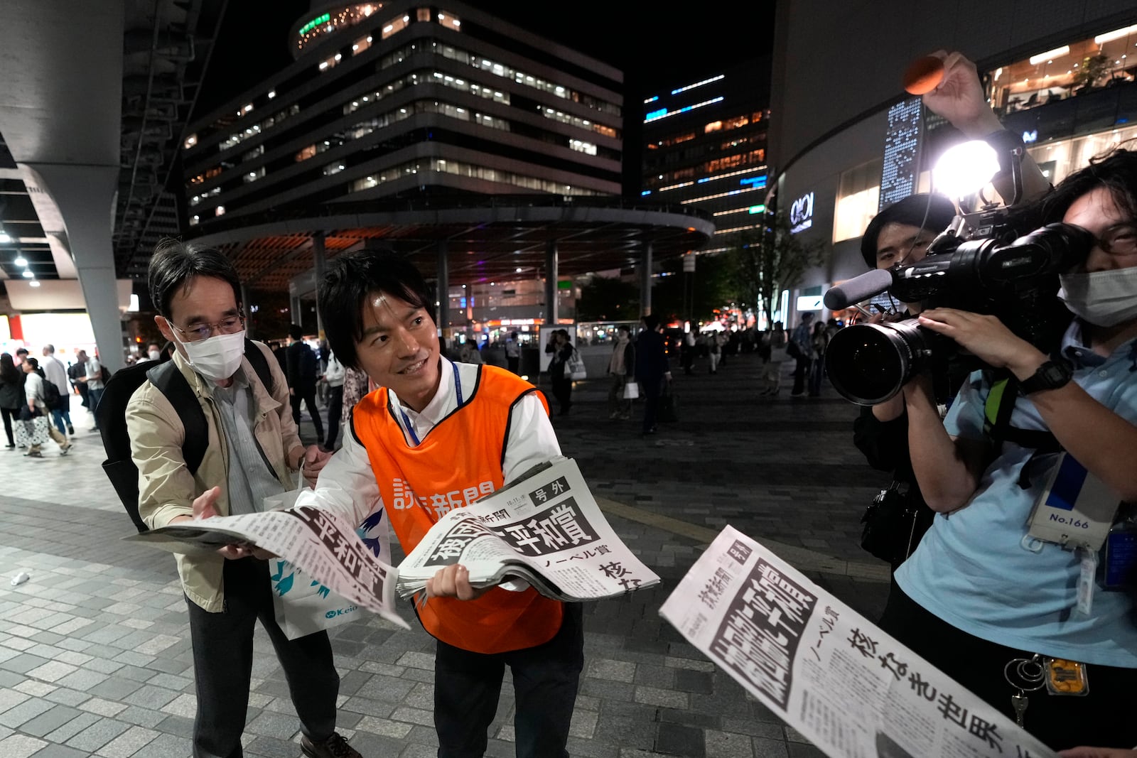 A worker of the Yomiuri Shimbun newspaper hands out copies of an extra version to passersby in Tokyo, Friday, Oct. 11, 2024, after Nihon Hidankyo, or the Japan Confederation of A- and H-Bomb Sufferers Organizations, won the Nobel Peace Prize. (AP Photo/Shuji Kajiyama)