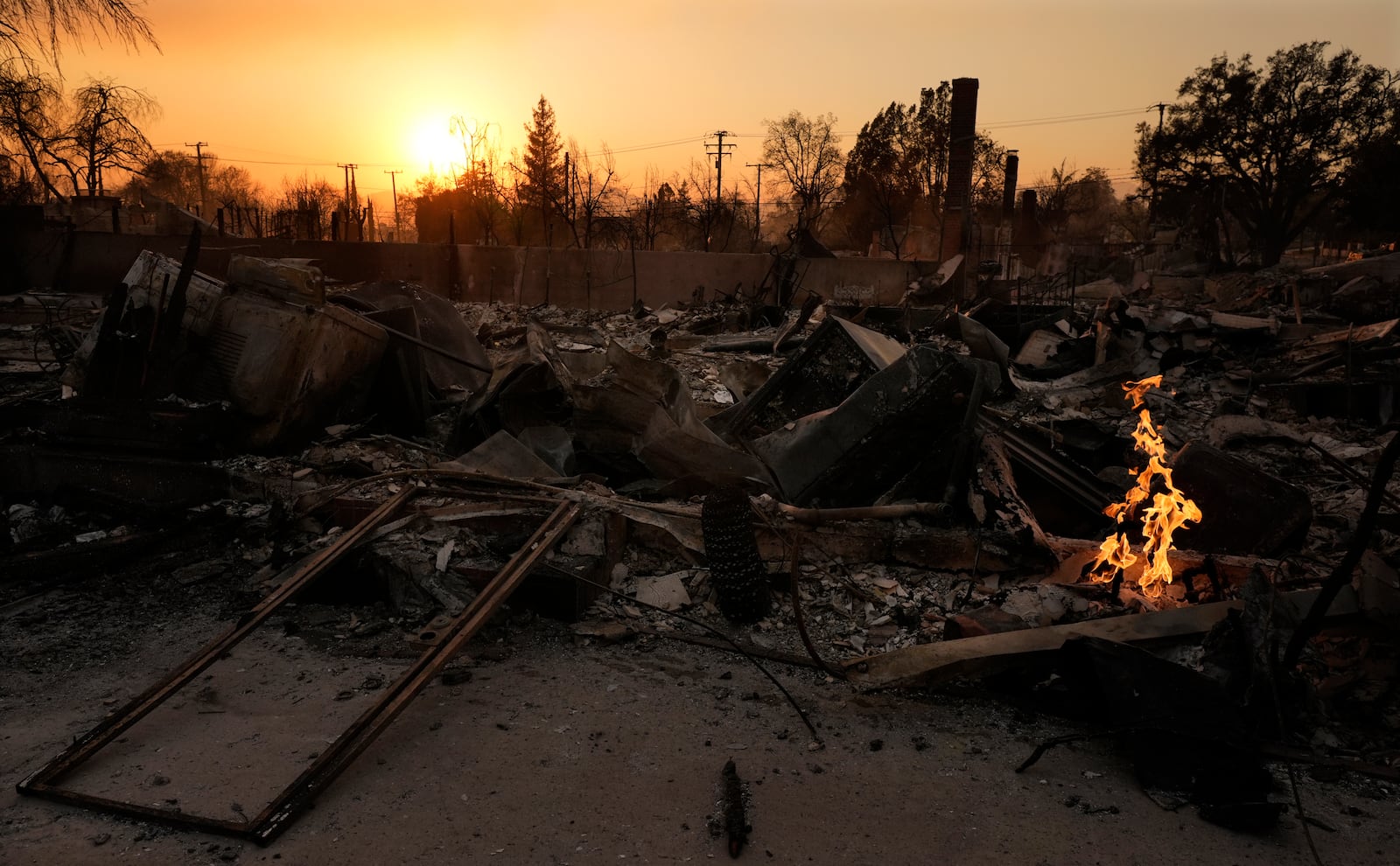 FILE - A small fire burns on the ruins of a house after it was destroyed by the Eaton Fire, Jan. 9, 2025, in Altadena, Calif. (AP Photo/Chris Pizzello, File)