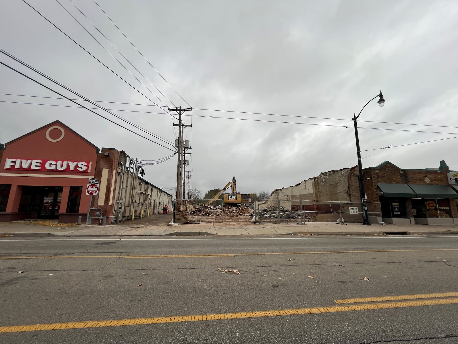 Crews tore down a former University of Dayton storage building at 1141 Brown St., located between Five Guys and the Submarine House in November 2024. The property owner hopes to bring a new Dutch Bros Coffee shop to the business strip. CORNELIUS FROLIK / STAFF