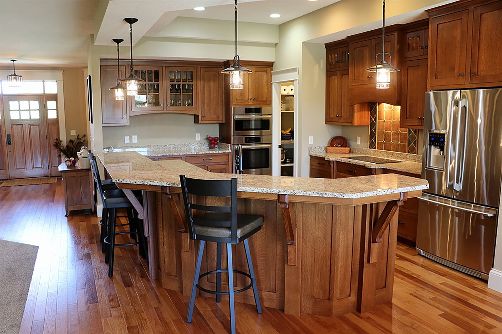 Matching corbels accent the large island that divides the kitchen from the great room. The island has seating for up to 8 along the elevated granite countertop while offering plenty or work space within the kitchen on the lower countertop. Slate-tile accents the wall space above the glass cook top. CONTRIBUTED PHOTO BY KATHY TYLER