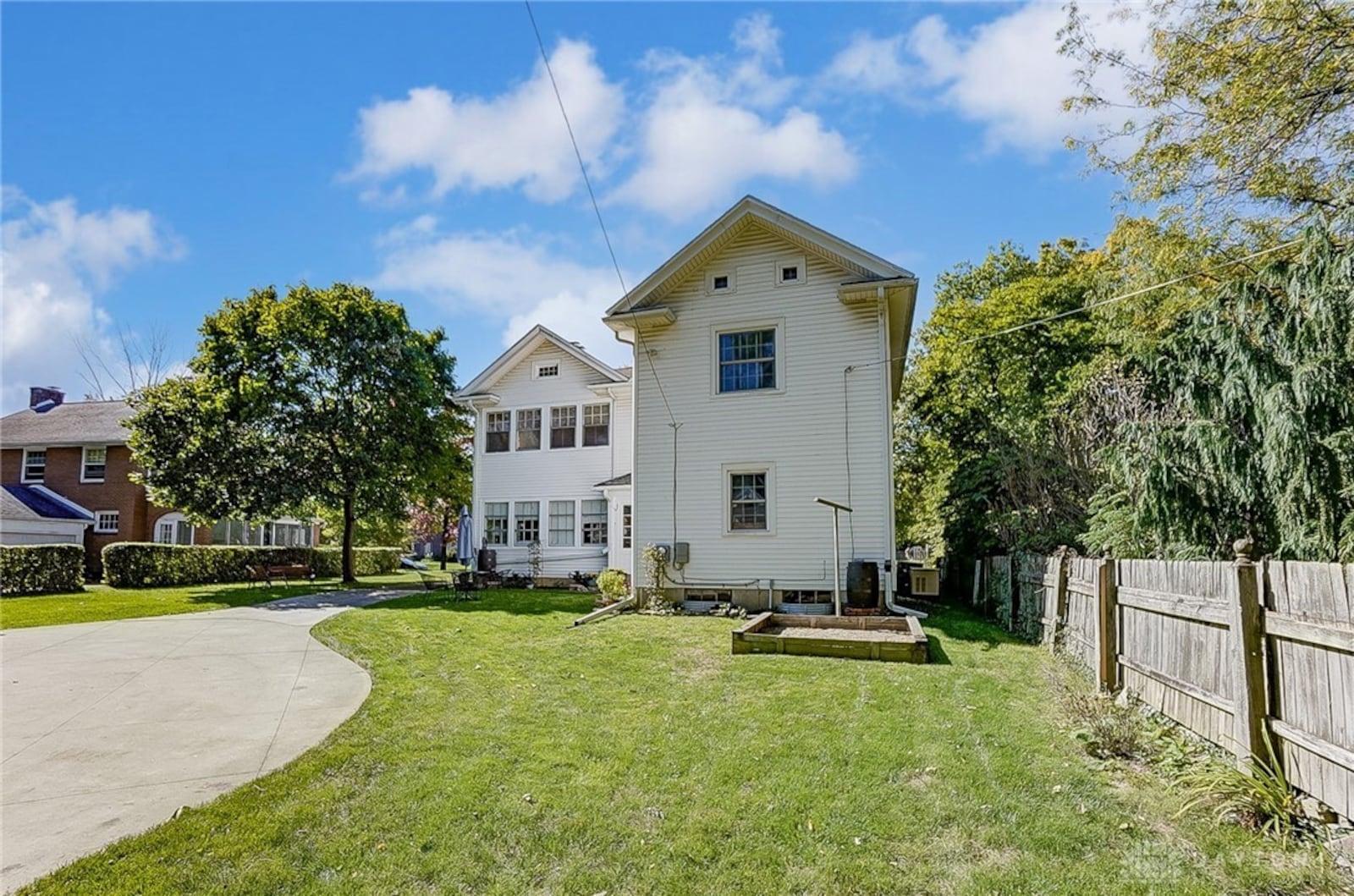 The rear of the home includes a concrete driveway connected to the garage and a yard with room for a garden and outdoor seating.