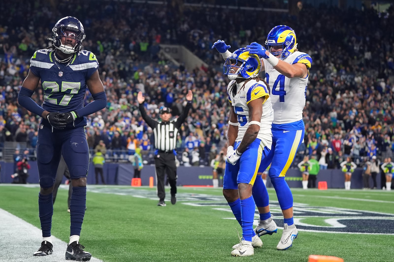 Seattle Seahawks cornerback Riq Woolen (27) reacts as Los Angeles Rams wide receiver Demarcus Robinson, middle, is congratulated by tight end Hunter Long after catching a touchdown pass during overtime of an NFL football game in Seattle, Sunday, Nov. 3, 2024. (AP Photo/Lindsey Wasson)