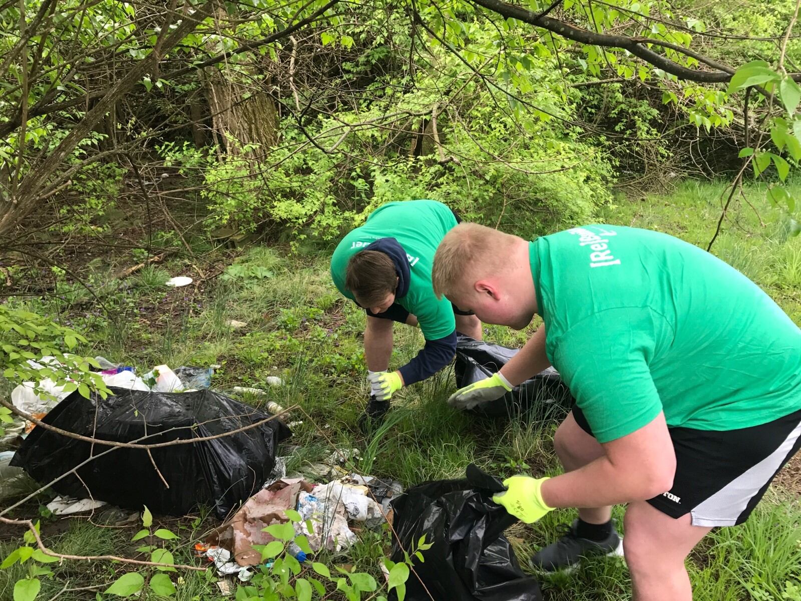 Dayton Flyers defensive tackle Joe Gits (right)  and center Dylan DeMaison pick up trash while trying to avoid the numerous discarded drug needles they found as they cleaned up around an abandoned house of Weaver Street Saturday. (Tom Archdeacon photo)