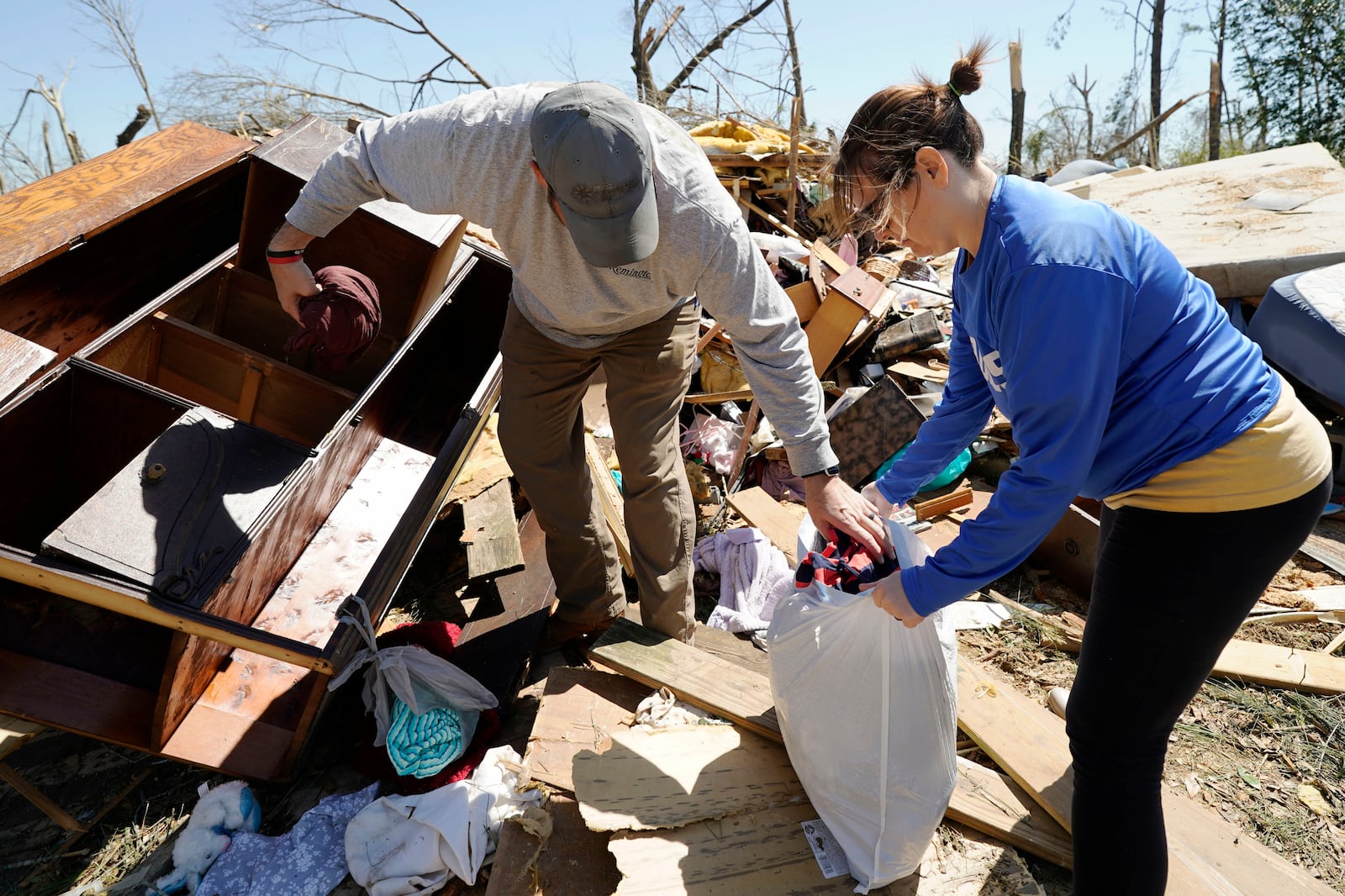 Tasha May, right, and her husband Tommy May, recover clothing from a cabinet in the tornado destroyed home of her grandparents, Sunday, March 16, 2025, Tylertown, Miss. (AP Photo/Rogelio V. Solis)