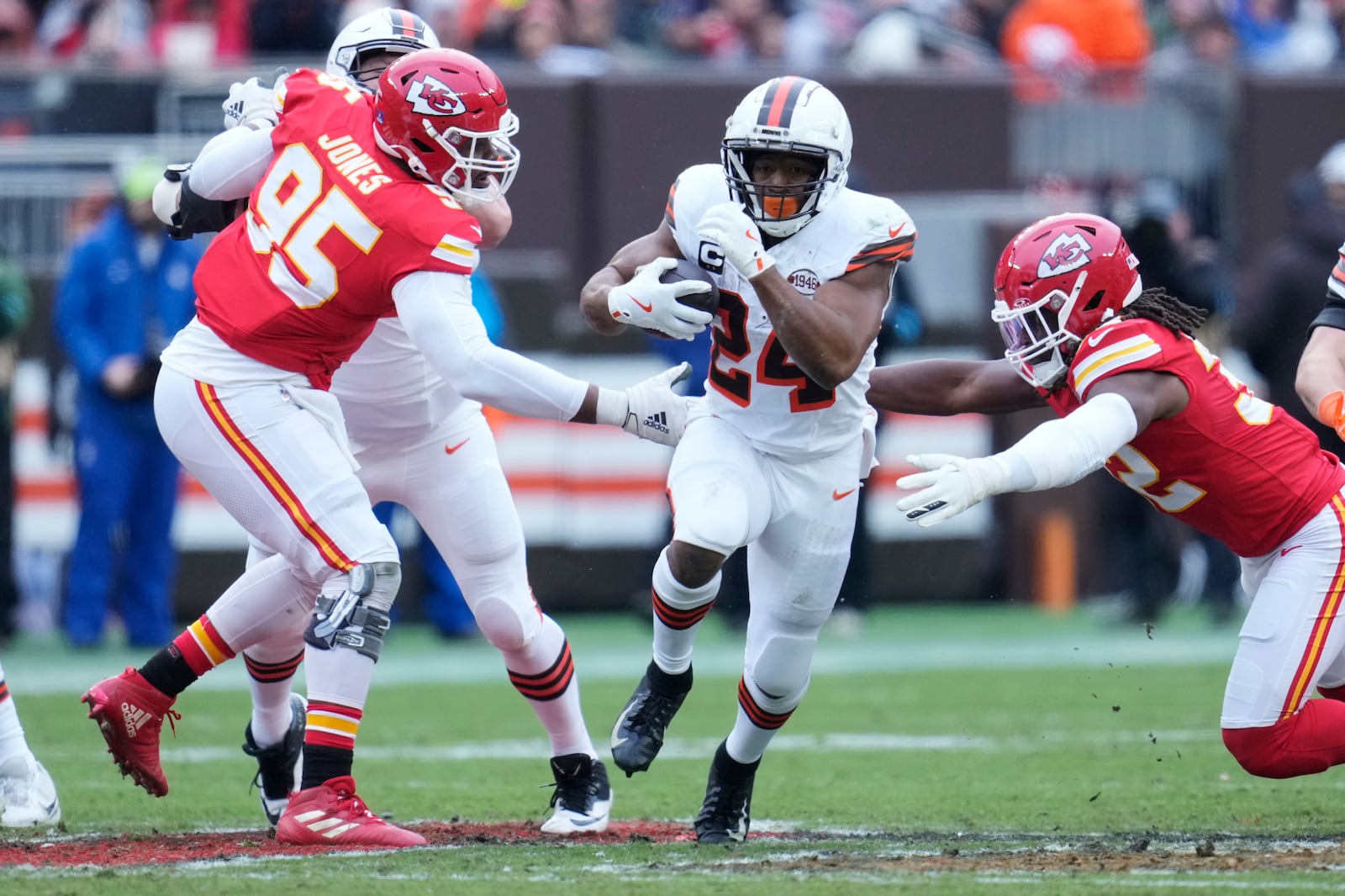 Cleveland Browns running back Nick Chubb, center, carries the ball between Kansas City Chiefs defensive tackle Chris Jones (95) and linebacker Nick Bolton, right, in the half of an NFL football game in Cleveland, Sunday, Dec. 15, 2024. (AP Photo/Sue Ogrocki)