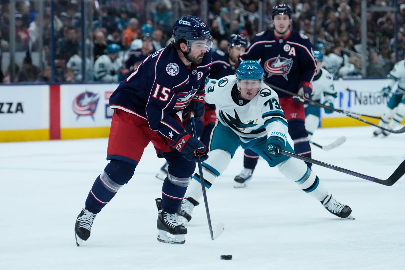 San Jose Sharks center Tyler Toffoli (73) reaches for the puck controlled by Columbus Blue Jackets defenseman Dante Fabbro (15) in the first period of an NHL hockey game Thursday, Jan. 16, 2025, in Columbus, Ohio. (AP Photo/Sue Ogrocki)