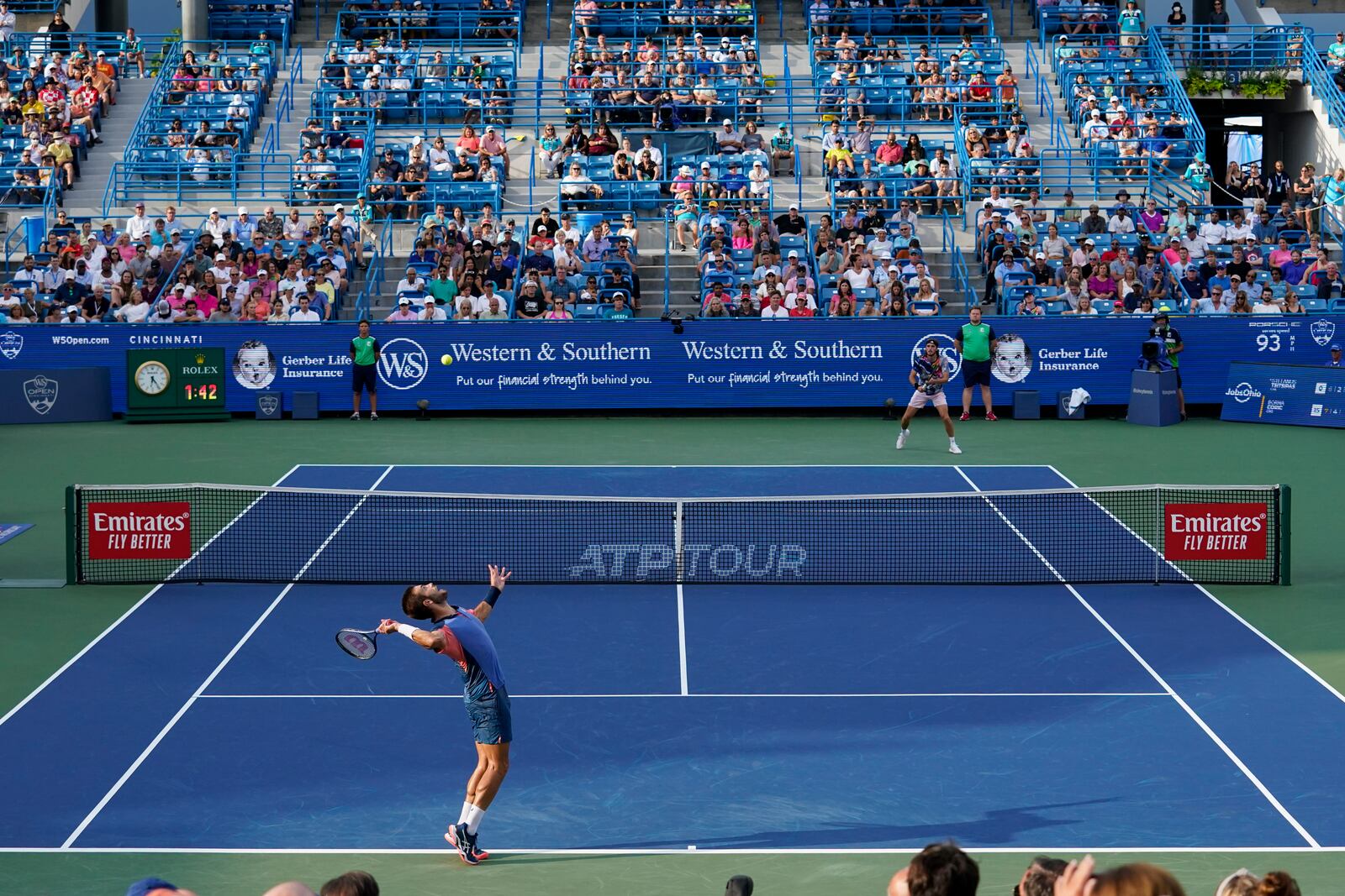 Borna Coric, bottom left, of Croatia, serves to Stefanos Tsitsipas, of Greece, during the men's singles final of the Western & Southern Open tennis tournament Sunday, Aug. 21, 2022, in Mason, Ohio. (AP Photo/Jeff Dean)