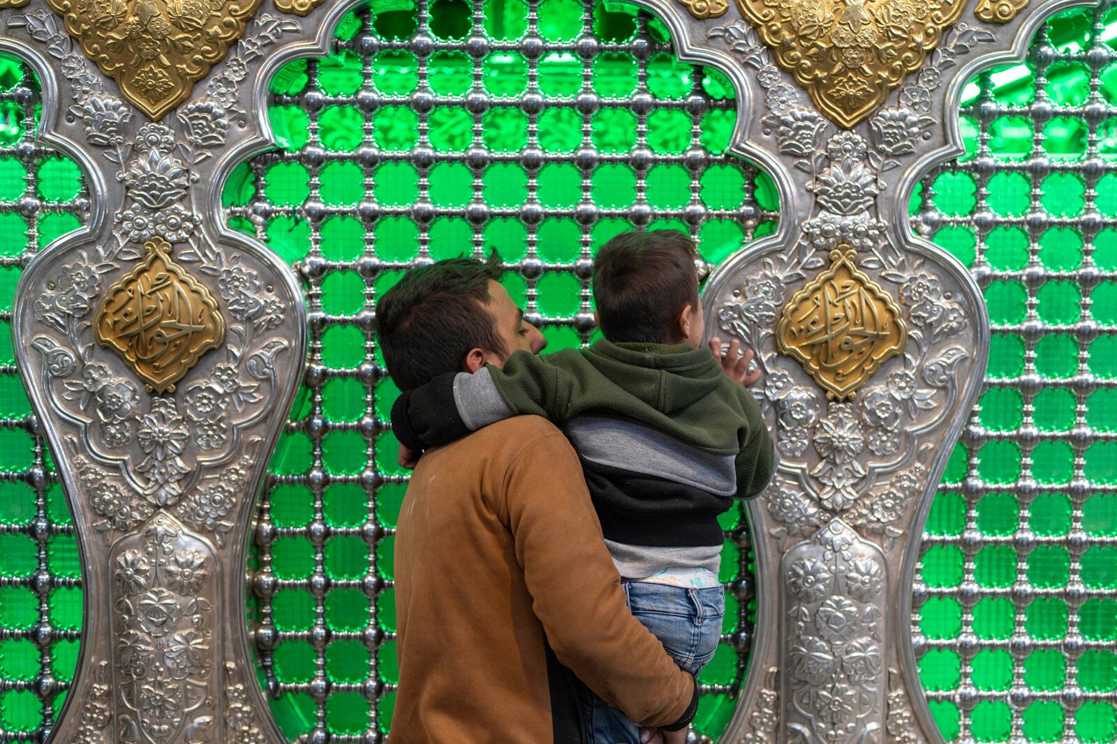 A man carries his child as they pray at the shrine of Sayyida Zaynab, the granddaughter of Prophet Mohammad, in Damascus, Syria, Saturday, Jan. 11, 2025. (AP Photo/Mosa'ab Elshamy)