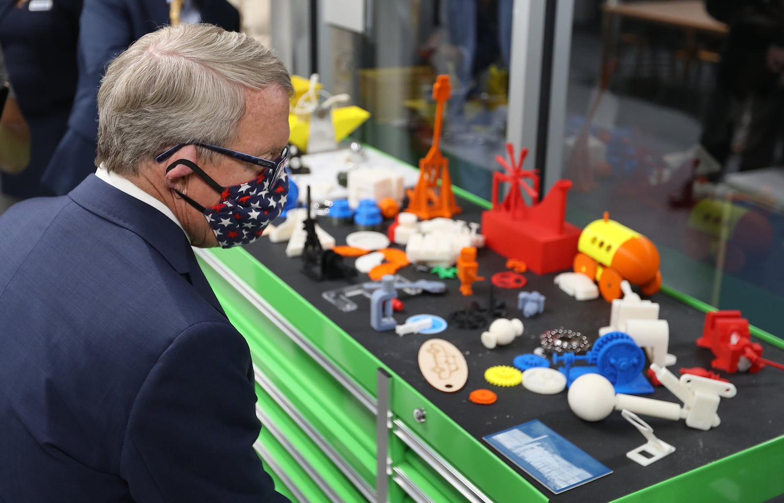 Governor Mike DeWine looks over some of the items the students have 3D printed Monday as he tours Clark State College's Advanced Manufacturing Lab. BILL LACKEY/STAFF