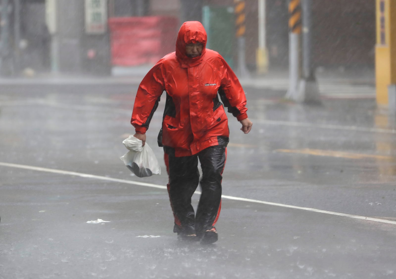 A woman struggles in the wind and rain generated by Typhoon Krathon in Kaohsiung, southern Taiwan, Thursday, Oct. 3, 2024. (AP Photo/Chiang Ying-ying)