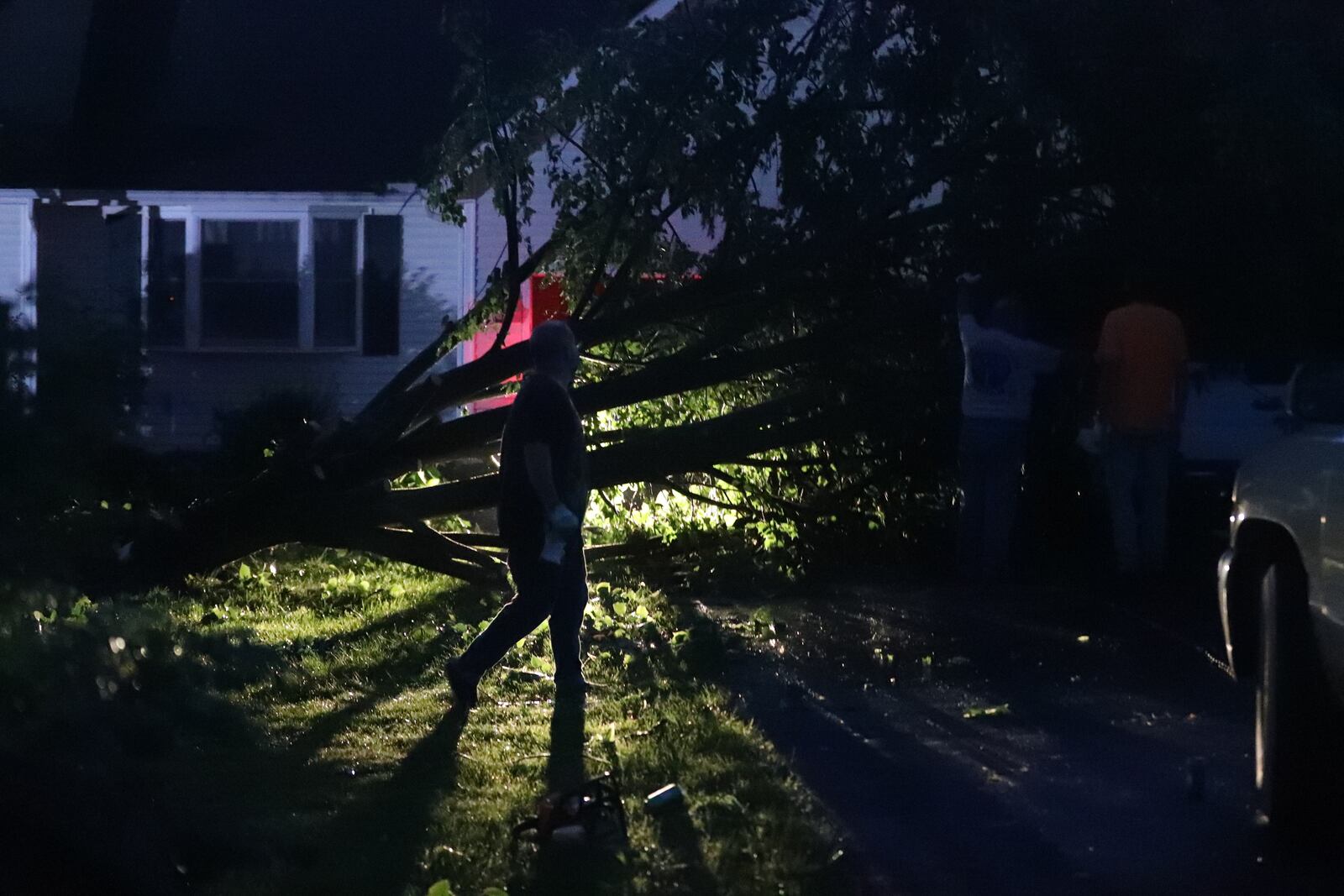 A woman walks past a tree that had fallen on two vehicles Wednesday, June 8, 2022, along Deer Run in German Twp. during Wednesday’s storm. BILL LACKEY/STAFF