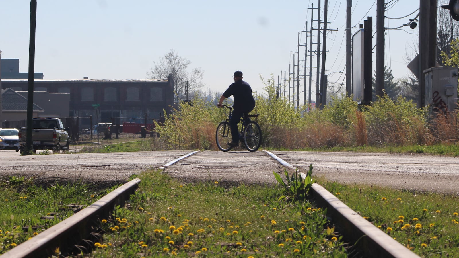 A man on a bicycle rides over a vacated rail line in East Dayton that the city of Dayton hopes to acquire and turn into a recreational trail. CORNELIUS FROLIK / STAFF