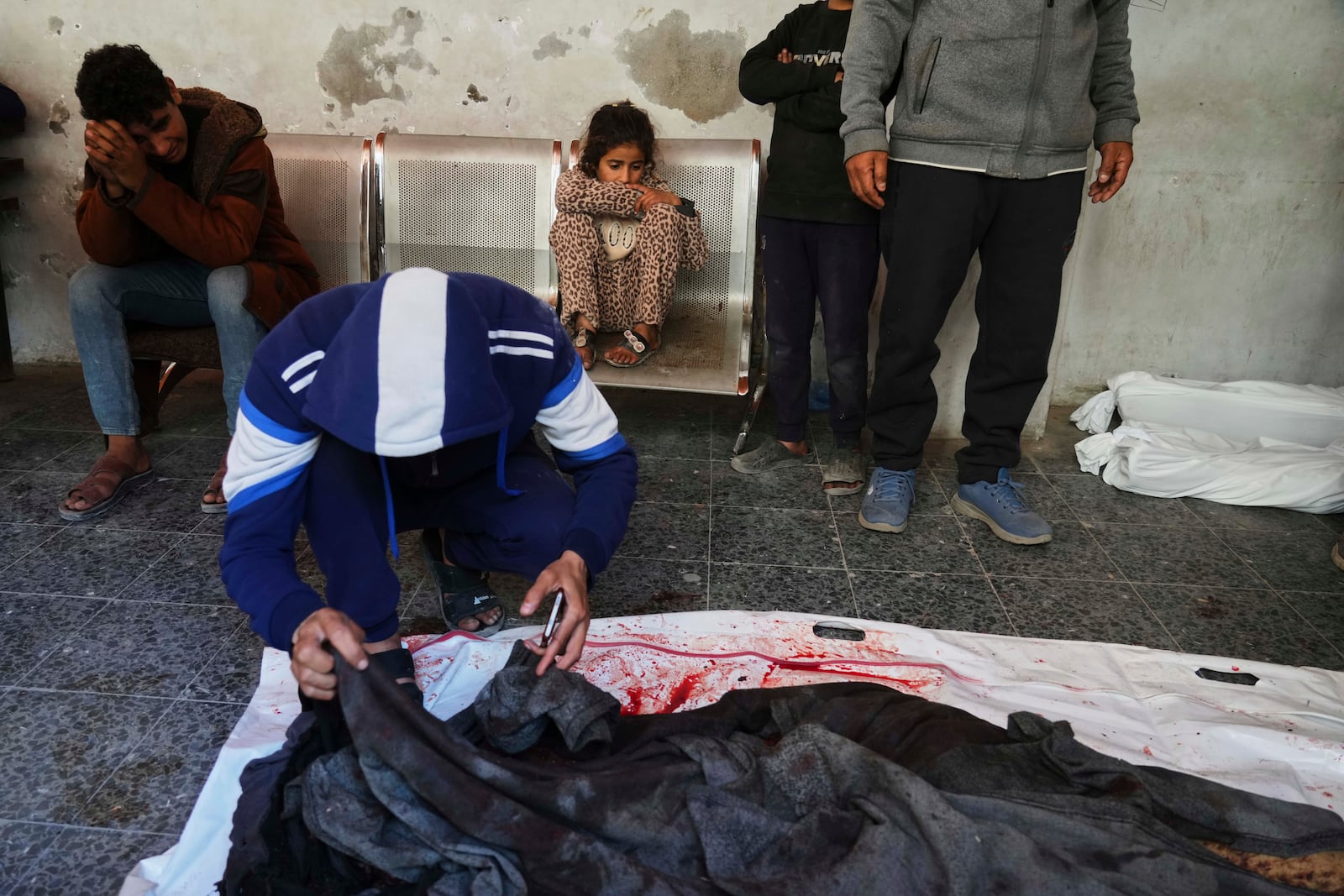 Palestinians mourn over the bodies of their relatives killed by an Israeli airstrike in the Netzarim corridor, at the Al-Ahli Hospital in Gaza City on Tuesday, March 11, 2025. (AP Photo/(AP Photo/Jehad Alshrafi)