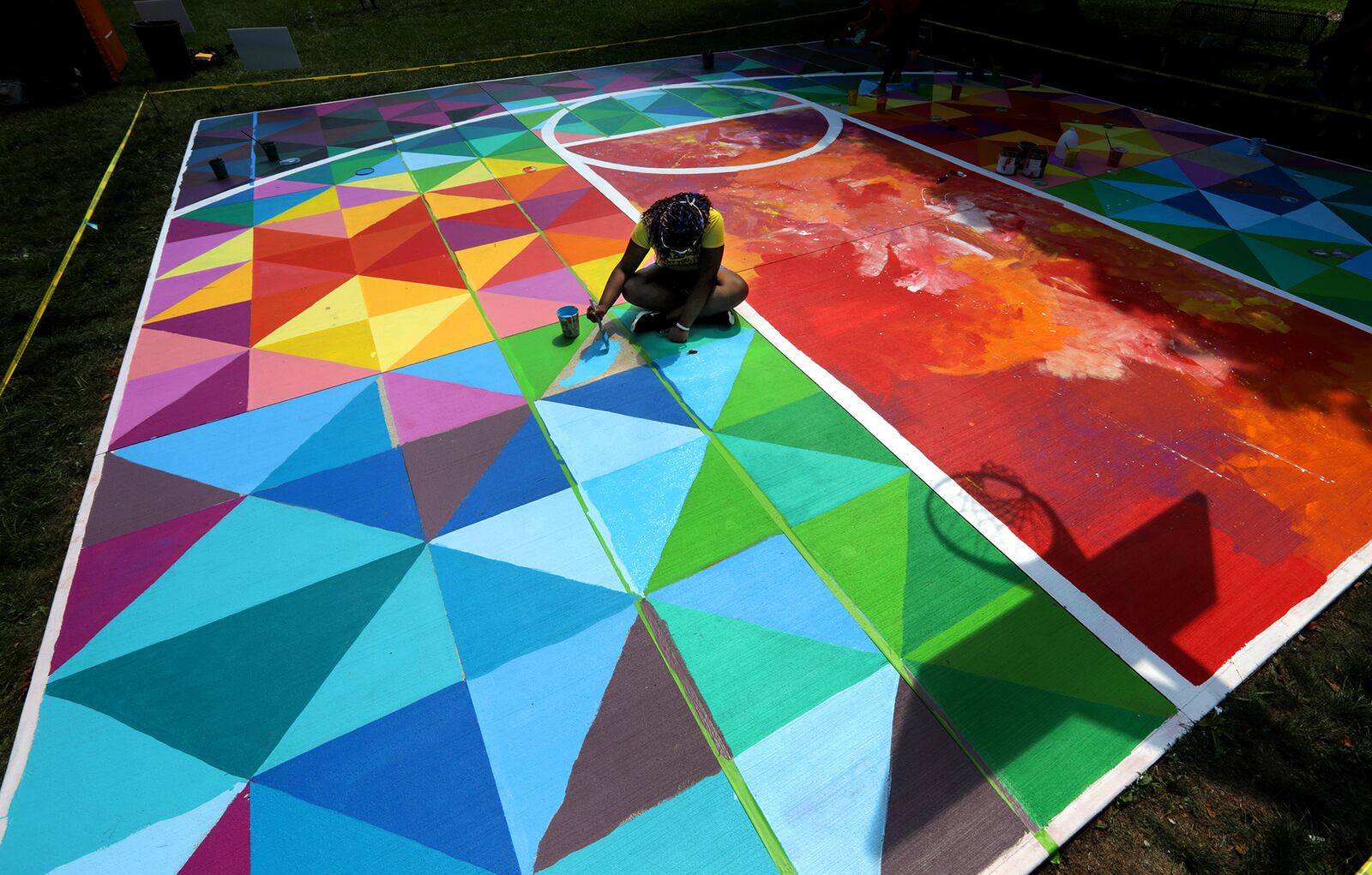 Saria Peterson, with Project Jericho, works on the new mural on a basketball court in a park along Woodward Avenue in Springfield. The mural was made possible through a partnership between Project Jericho and the Conscious Connect, Inc. BILL LACKEY/STAFF