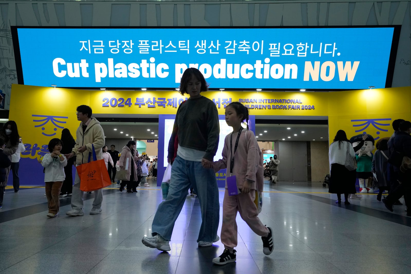 People pass by an electric display board calling for a reduction in plastic production near the venue for the fifth session of the Intergovernmental Negotiating Committee on Plastic Pollution in Busan, South Korea, Saturday, Nov. 30, 2024. (AP Photo/Ahn Young-joon)