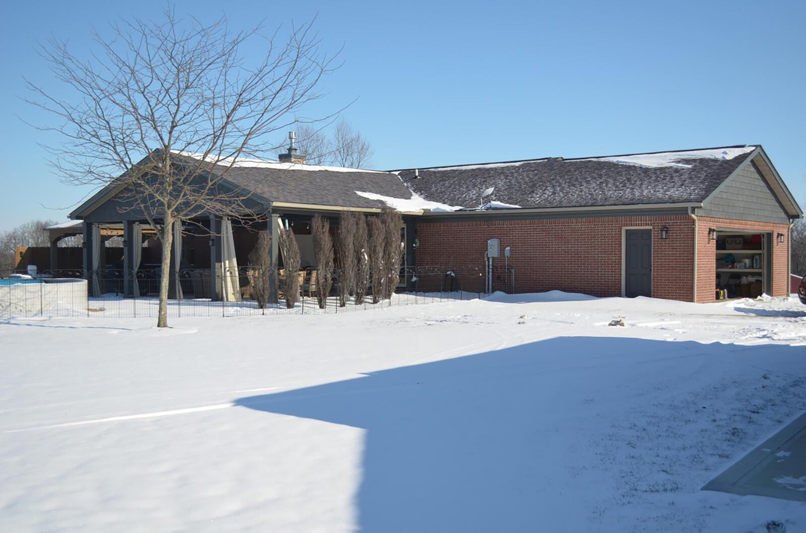 The rear of the home has a covered patio, a wood pergola covering a hot tub and an above ground pool.