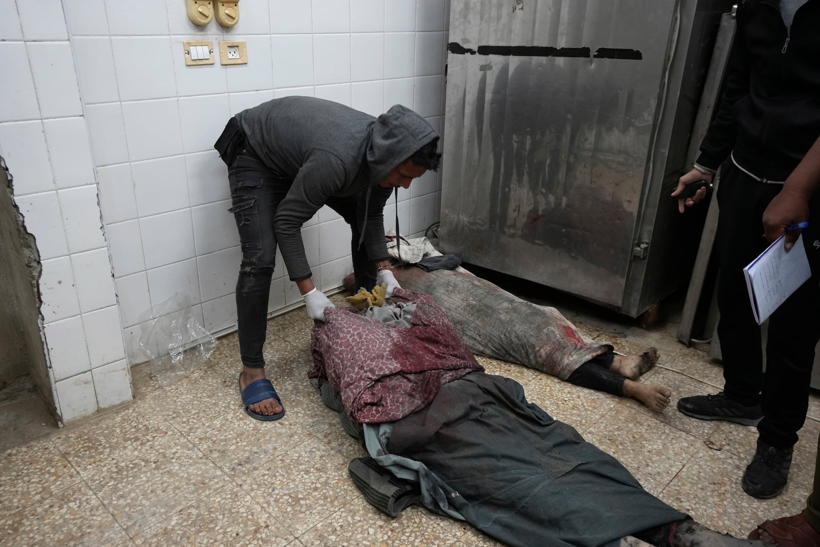 Palestinians killed in an Israeli strike on a building are checked in the morgue at Al-Aqsa Hospital in Deir al-Balah, Gaza Strip, Thursday, Dec. 12, 2024. (AP Photo/Abdel Kareem Hana)