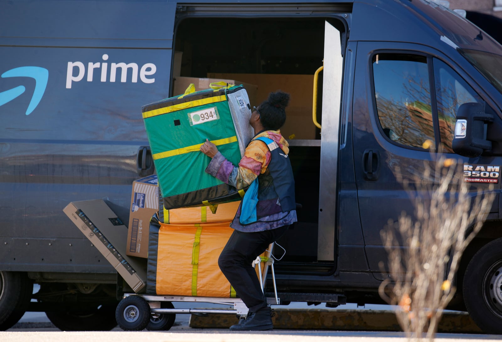 FILE - An Amazon Prime delivery person lifts packages while making a stop on Nov. 28, 2023, in Denver. (AP Photo/David Zalubowski, File)