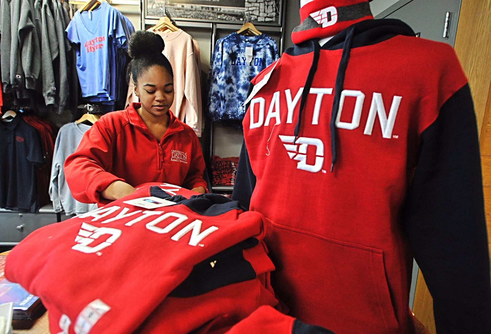 Victorya White, sales associate, supervisor at the UD Flyer Spirit Store on Brown Street, folds red and blue sweatshirts. Staff Photo Marshall Gorby