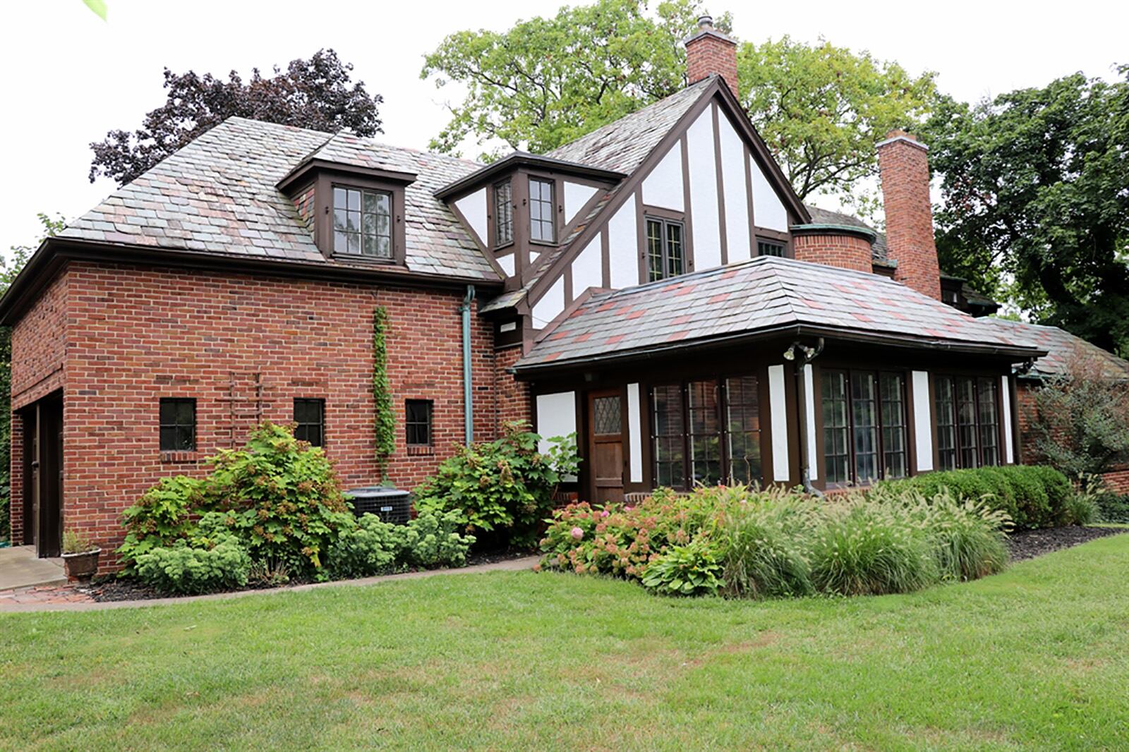 The tiered back yard has a paver-brick patio with stone accents and fire ring. The patio leads to a summer house which opens into a 4-season space with woodgrain tile flooring, wood-beam ceiling, built-in cabinetry and countertops, and a brick wood-burning fireplace. CONTRIBUTED PHOTO BY KATHY TYLER