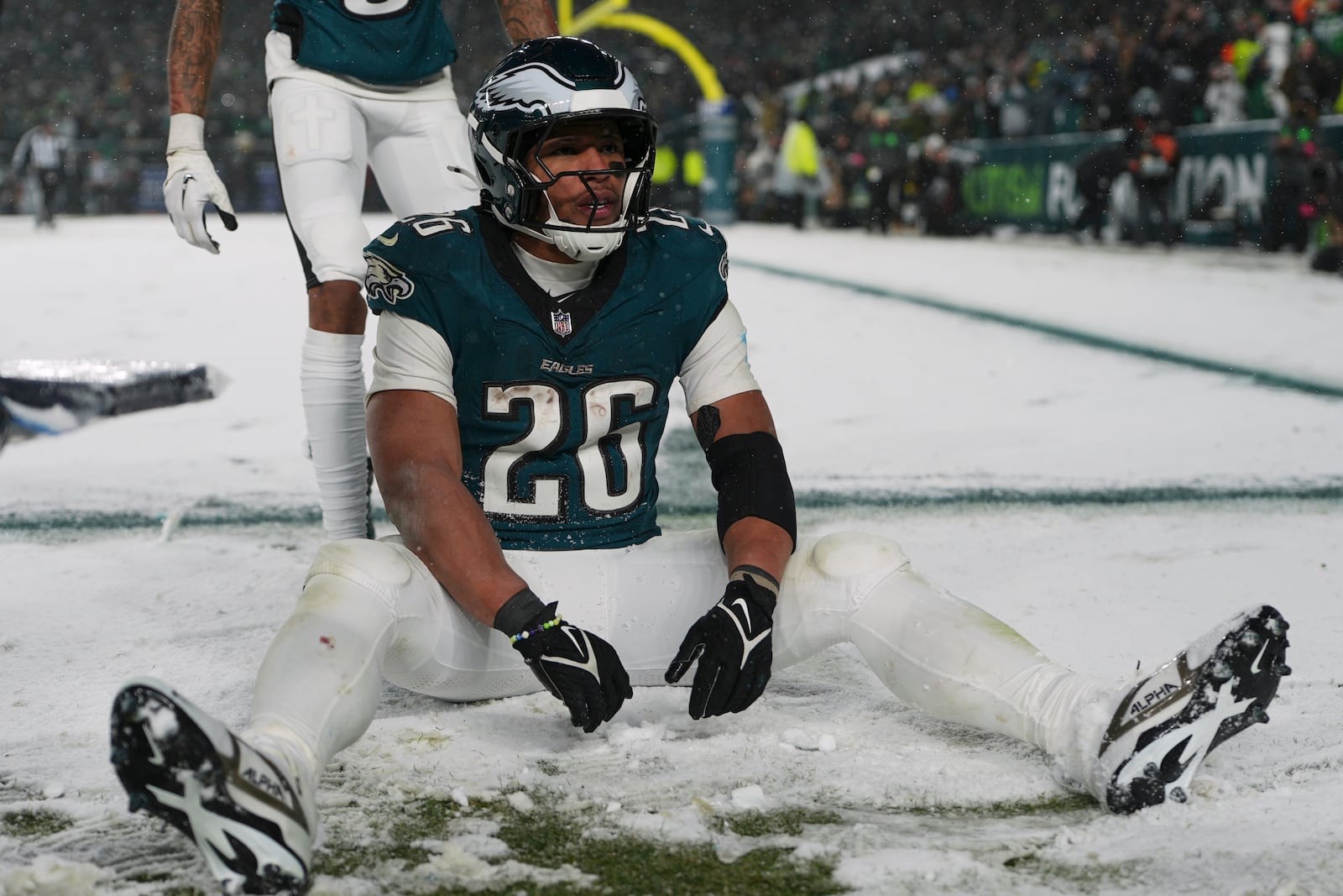 Philadelphia Eagles running back Saquon Barkley (26) sits in the snow as he celebrates his touchdown during the second half of an NFL football NFC divisional playoff game against the Los Angeles Rams on Sunday, Jan. 19, 2025, in Philadelphia. (AP Photo/Matt Slocum)