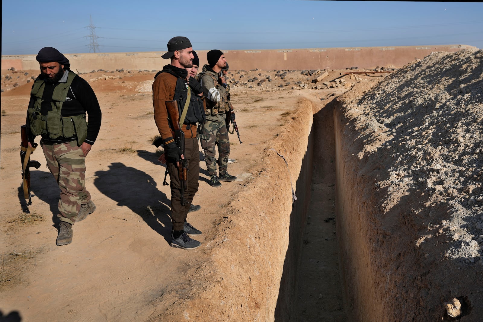 Syrian fighters from rebel group, observe a location identified as a mass grave for detainees killed under rule of Bashar Assad in Najha, south of Damascusn Najha, south of Damascus, Syria, Tuesday, Dec. 17, 2024. (AP Photo/Hussein Malla)